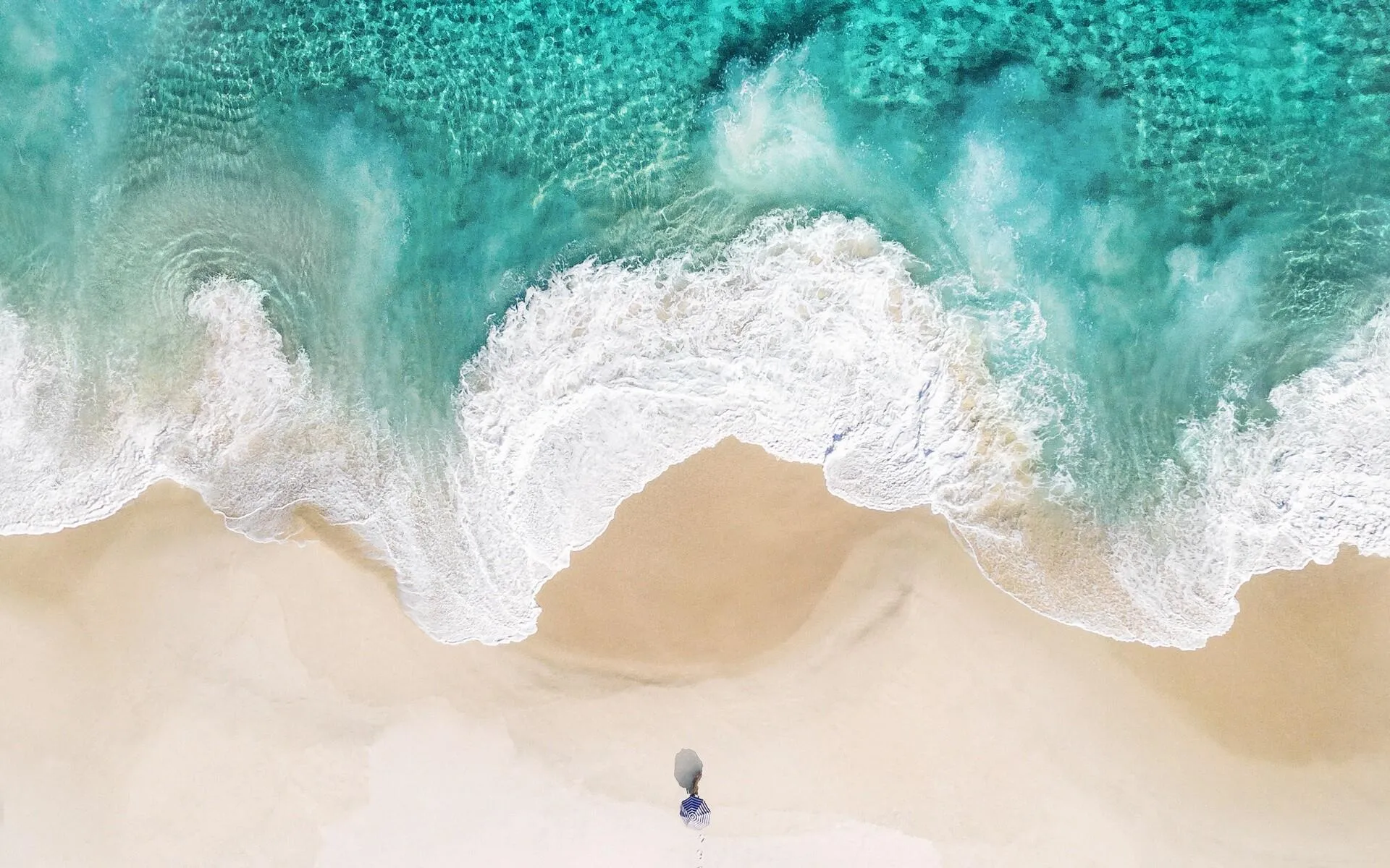 Aerial View of Waves Meeting a Soft Golden Sand Beach Shore