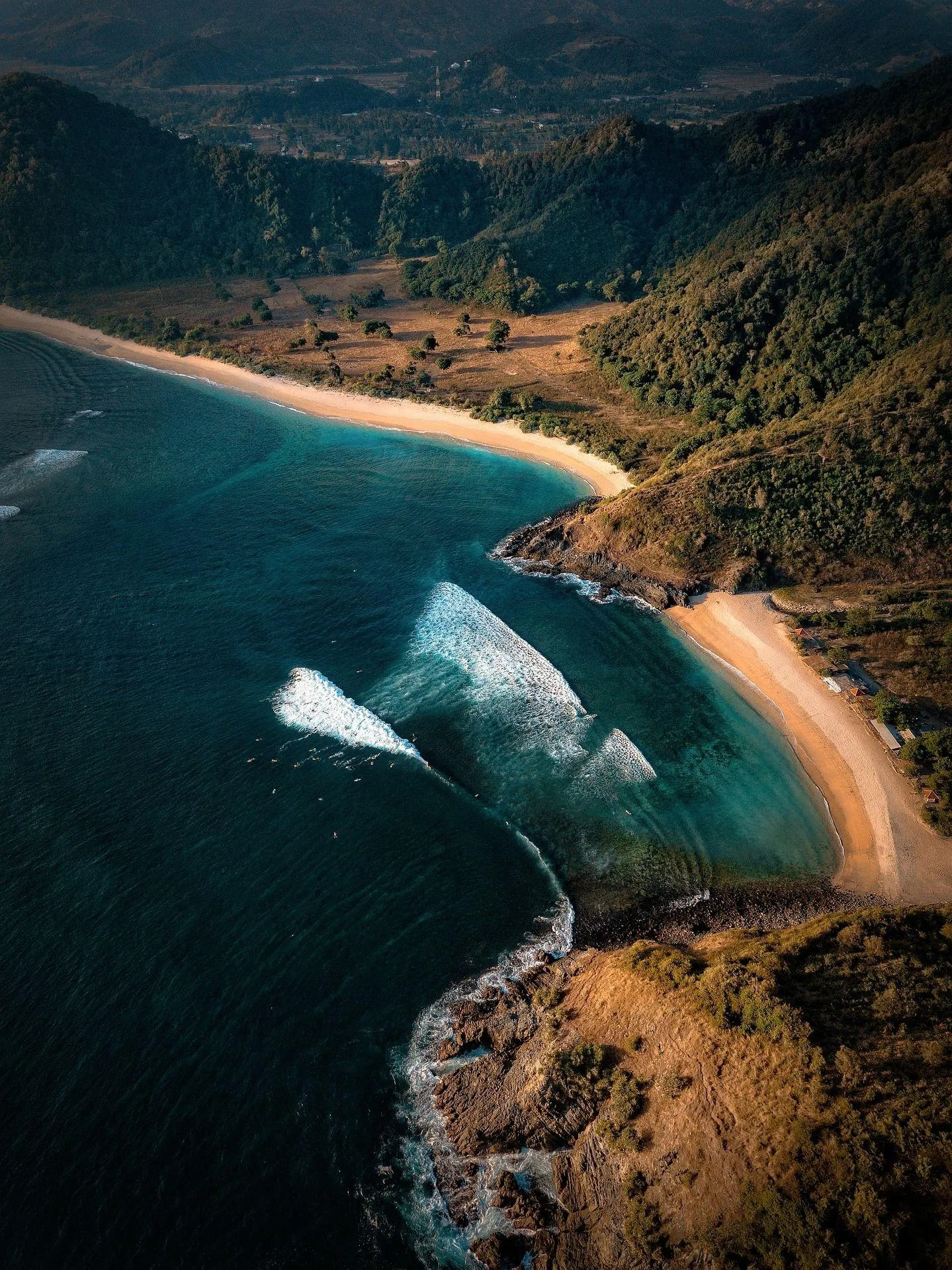 Aerial View of a Winding Coastline with Lush Green Hillside