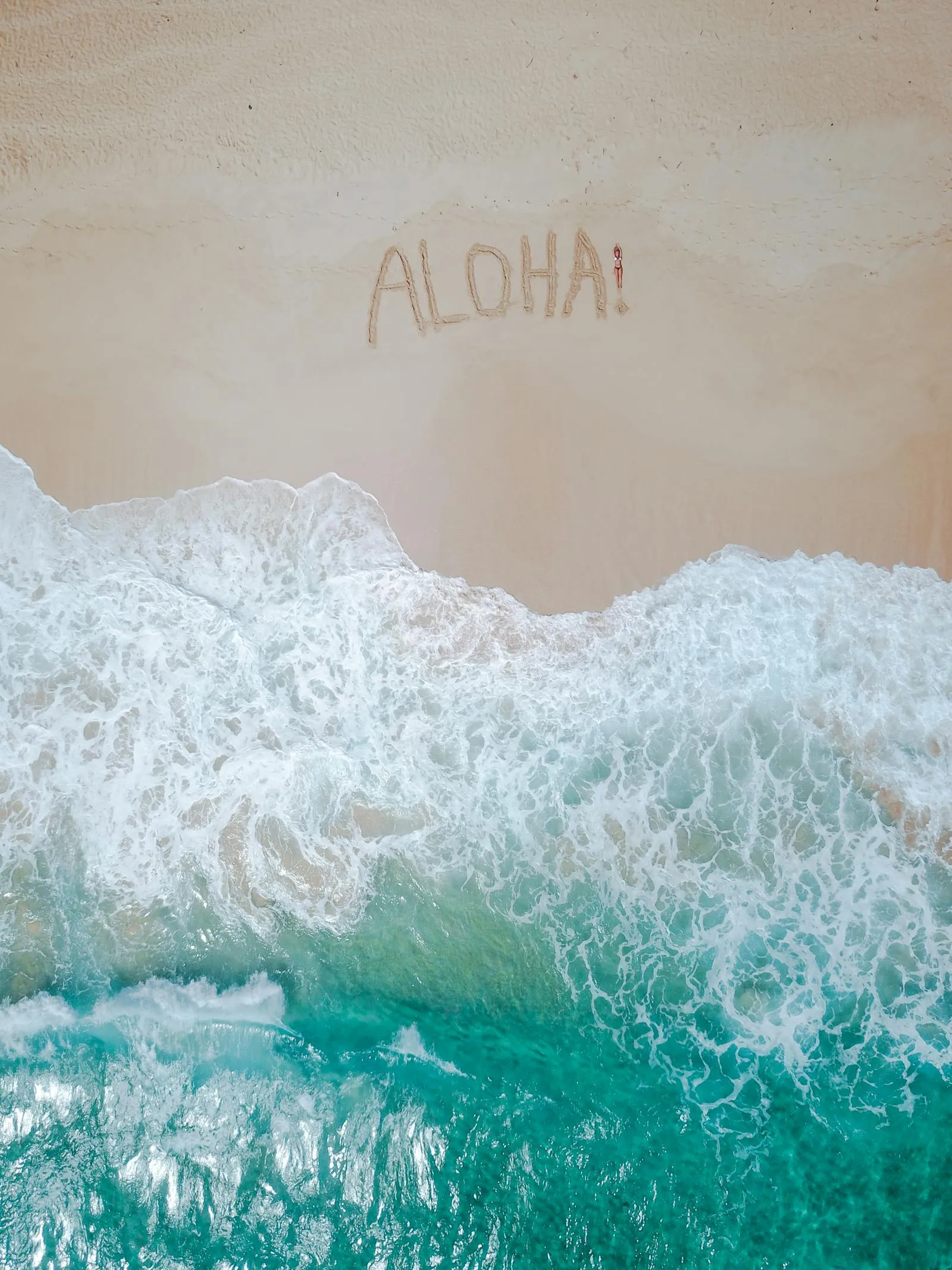 Beach with Waves Washing over the Aloha Word in the Sand