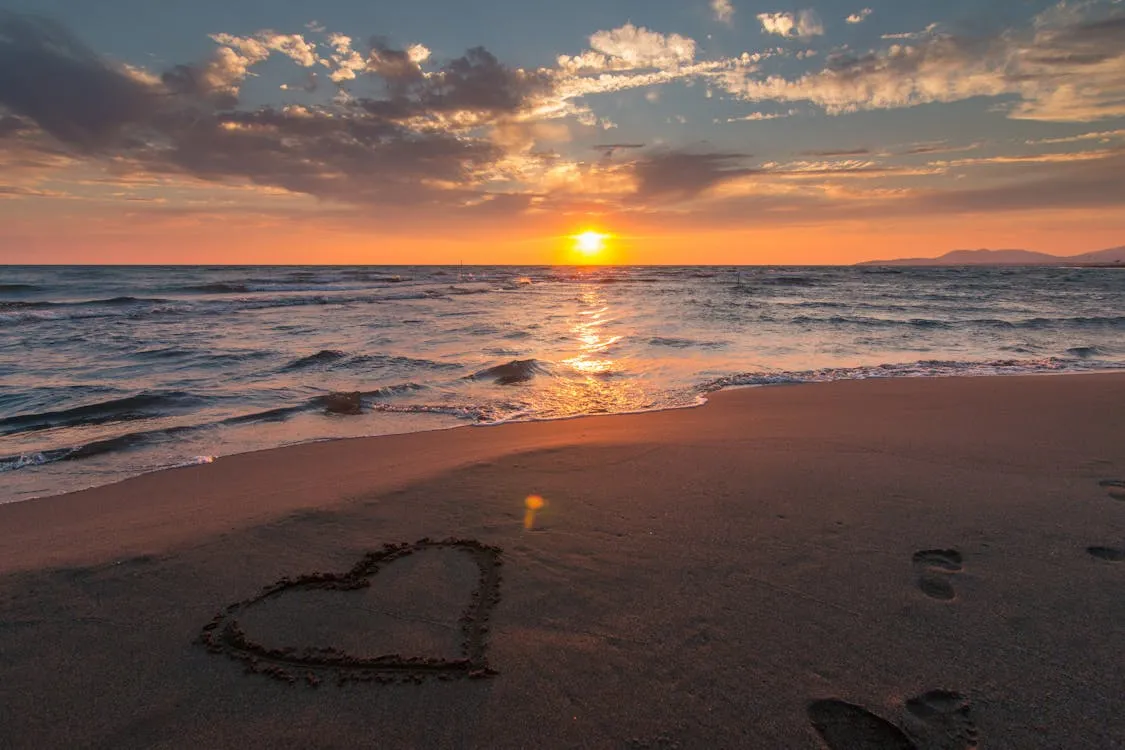 Beautiful Sunset on the Beach with a Heart Shape in the Sand