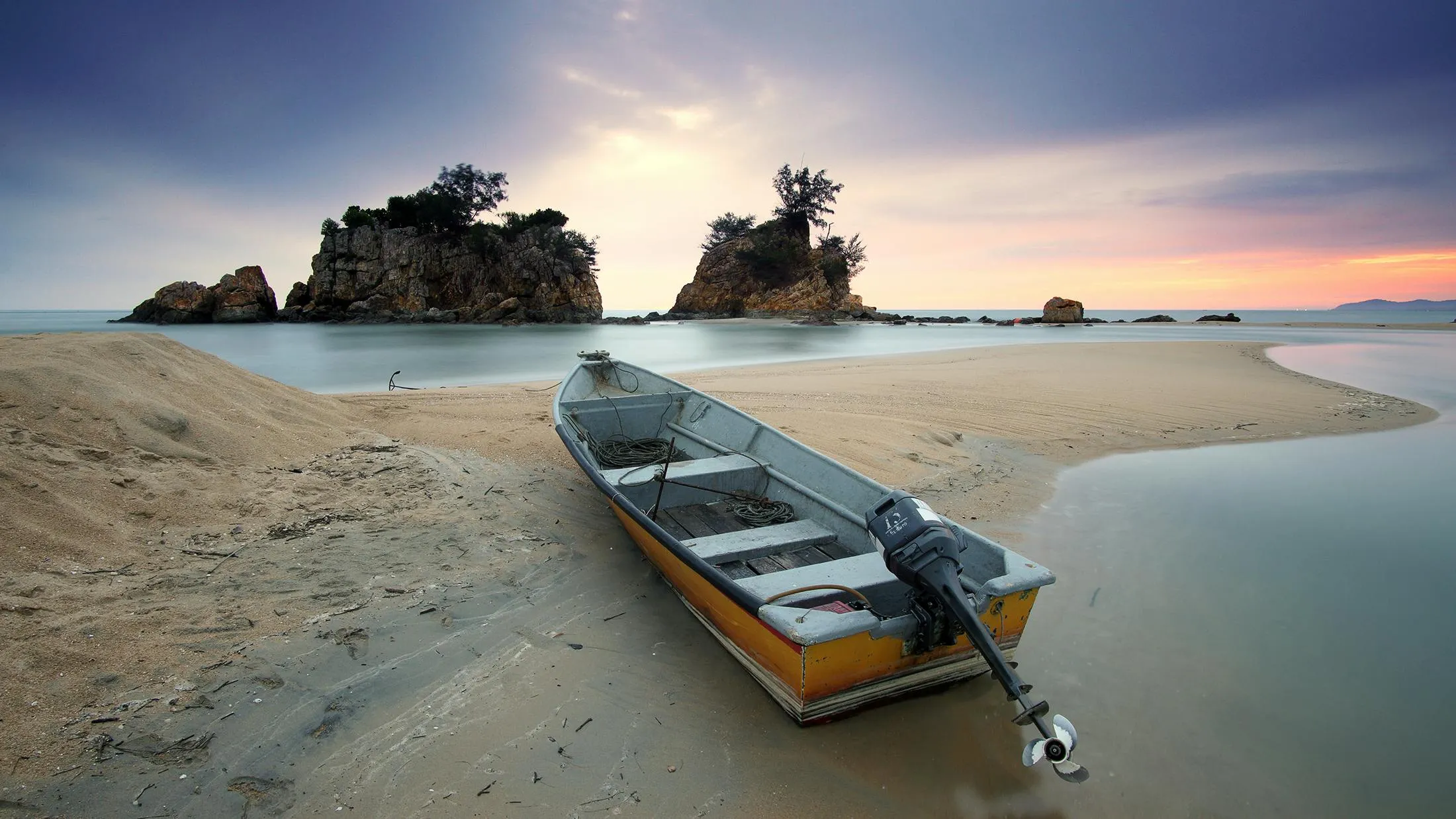 Boat Resting on Sandy Beach at Sunset with Calm Sea and Sky