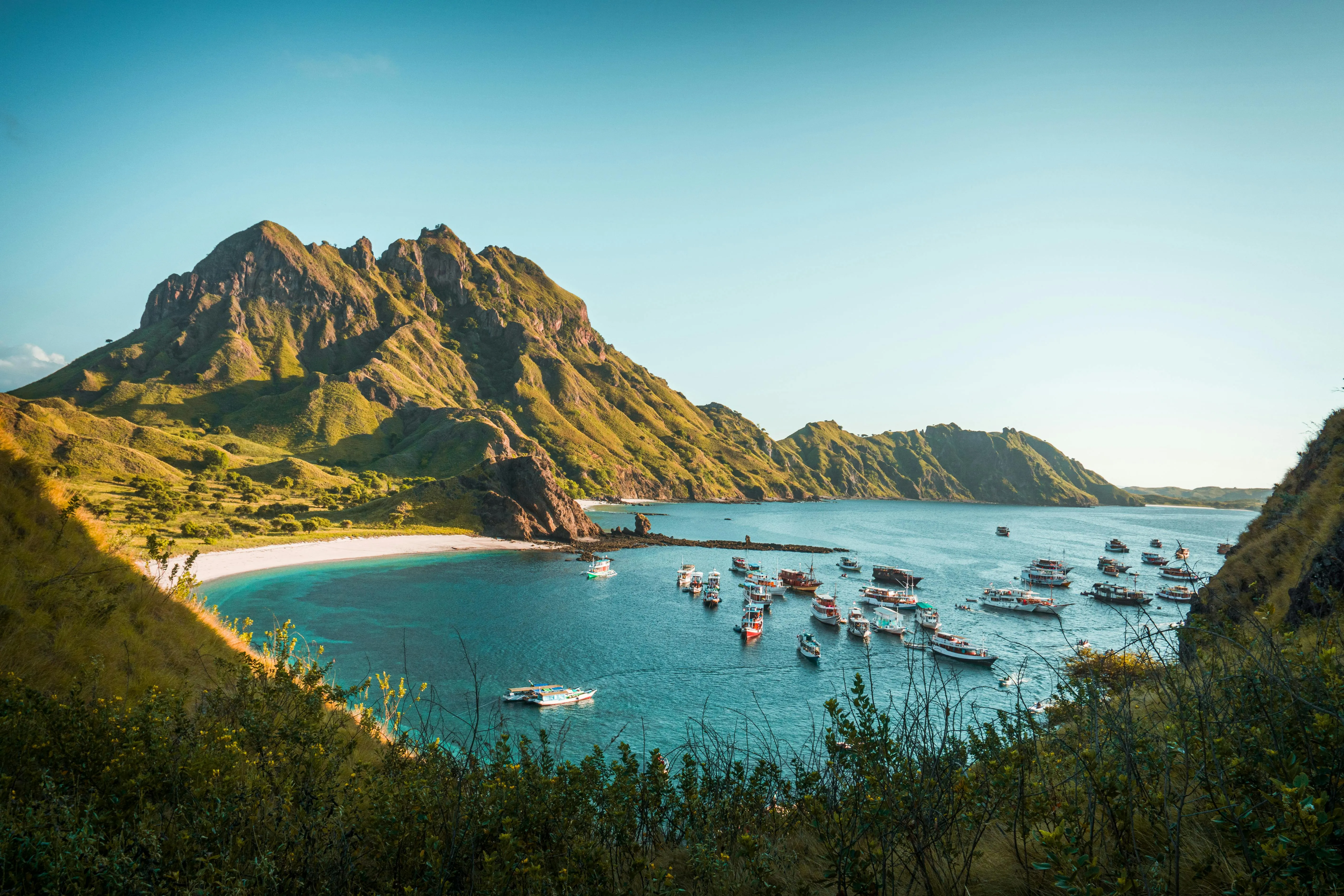 Boats are Anchored Near Rocky Coastal Hills in Sunlight