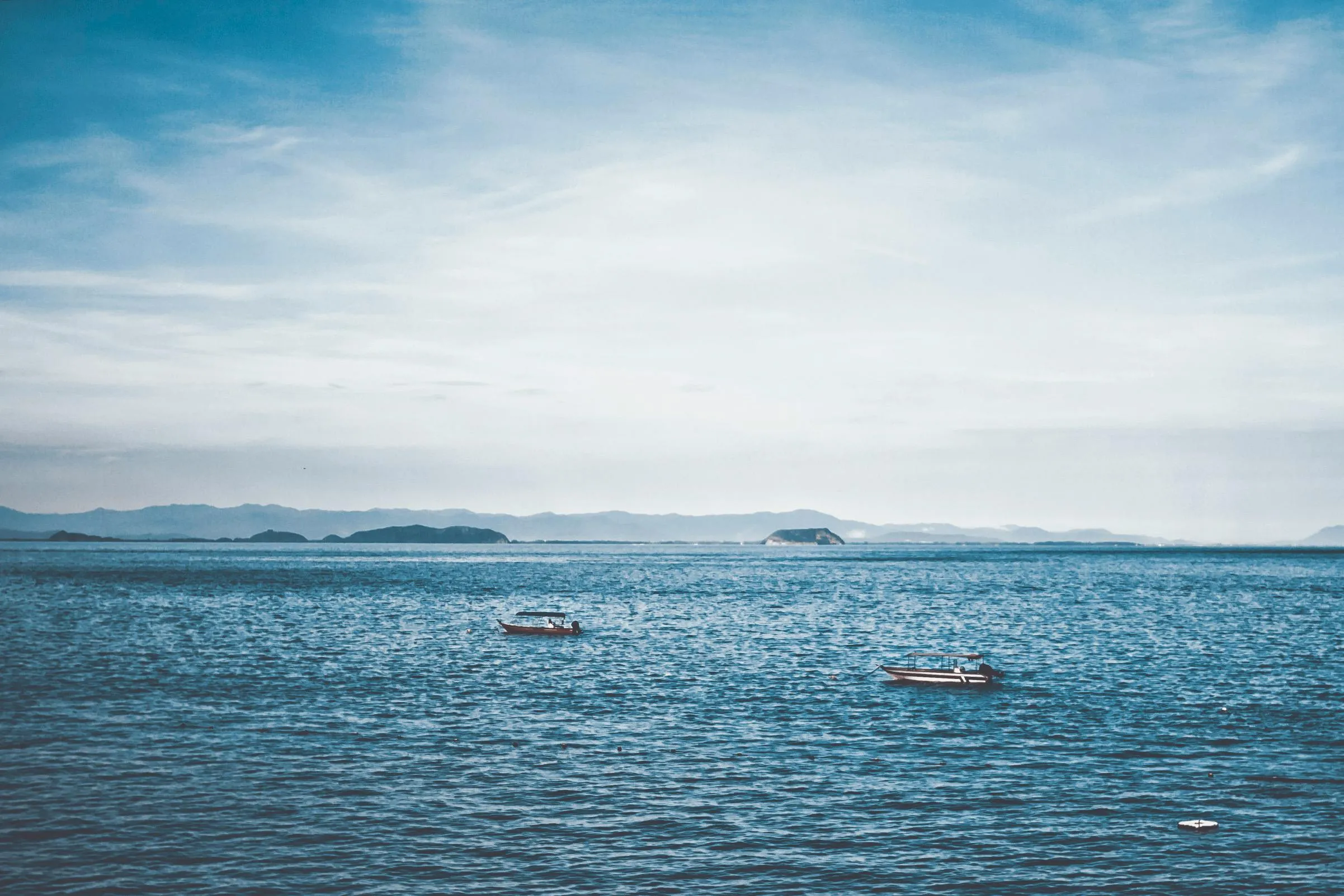 Boats Floating in a Calm Ocean Under a Wide Blue Sky