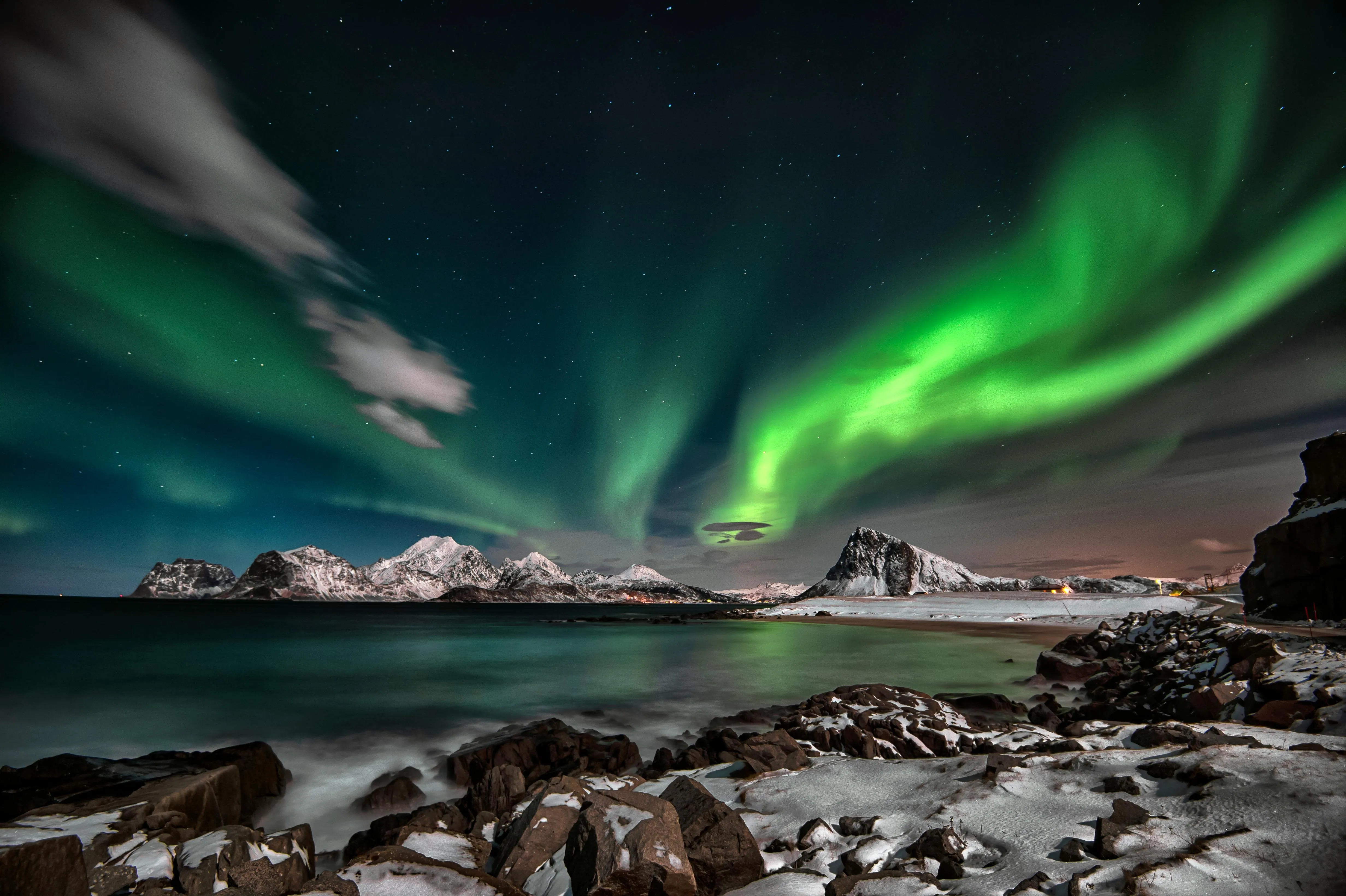 Bright Green Aurora Lights over Snow and a Rocky Beach