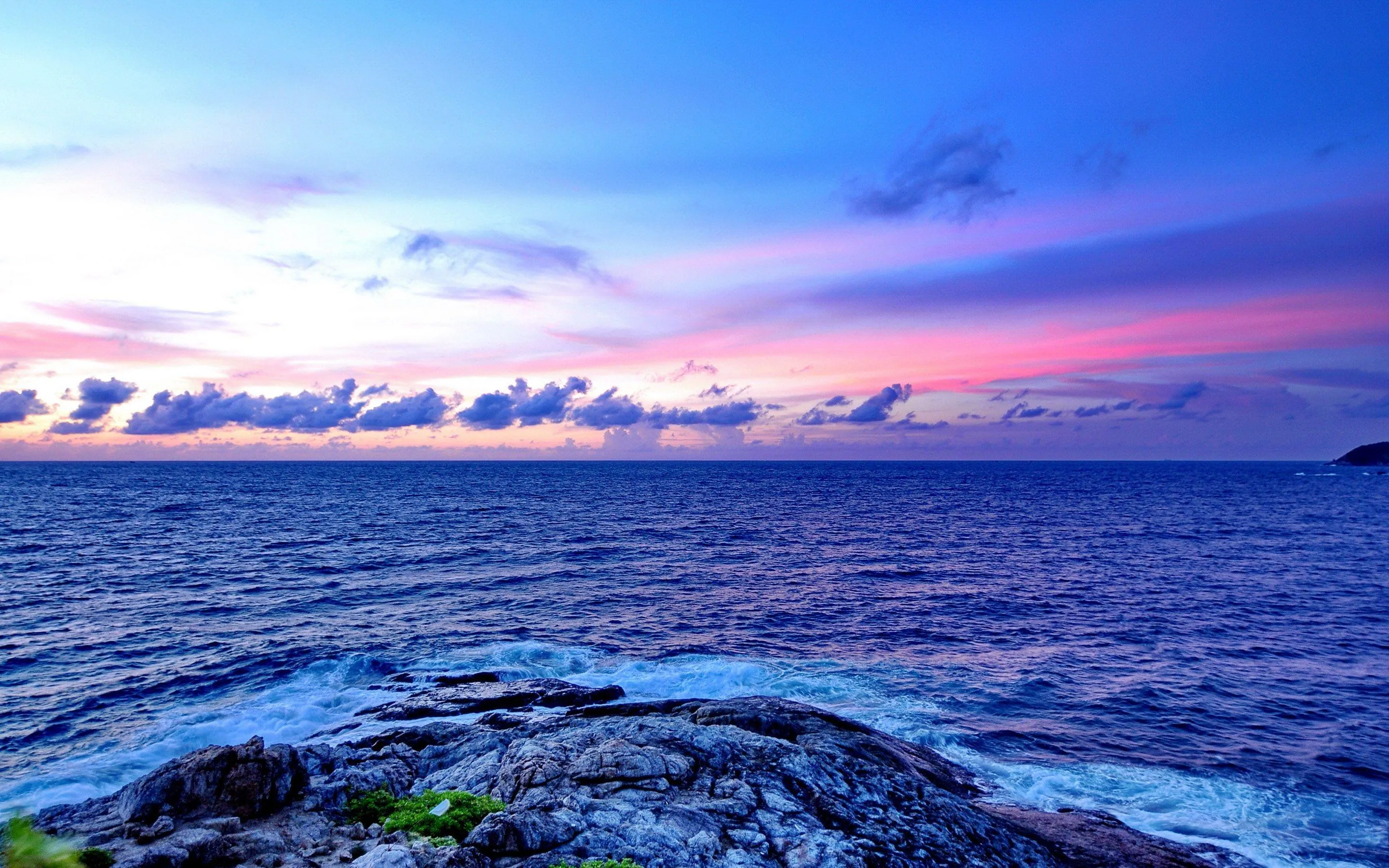 Calm Ocean Meets Rocky Coast Under Soft Evening Sky