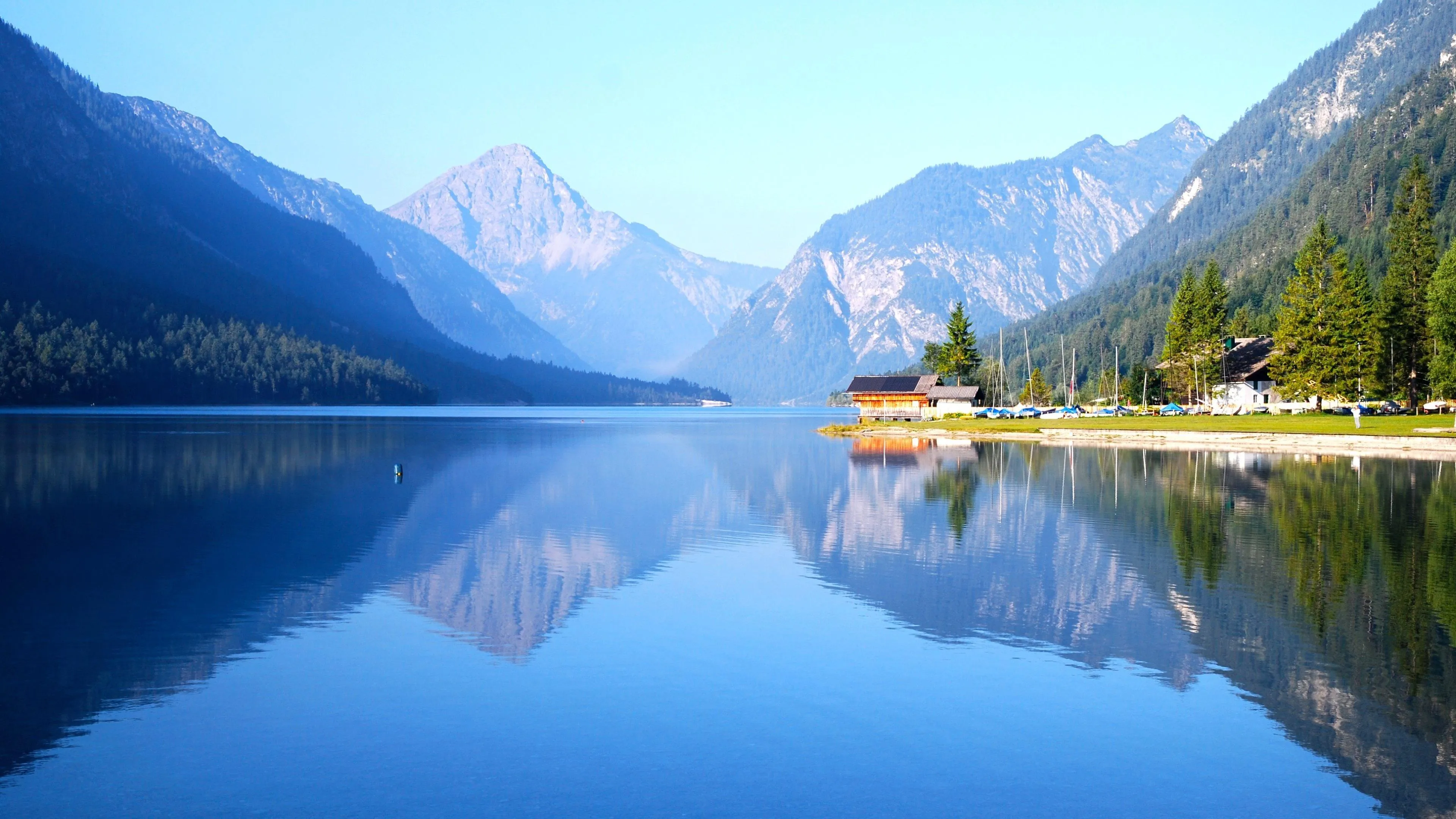 Clear Lake Surrounded by Tall Green Mountains and Sky
