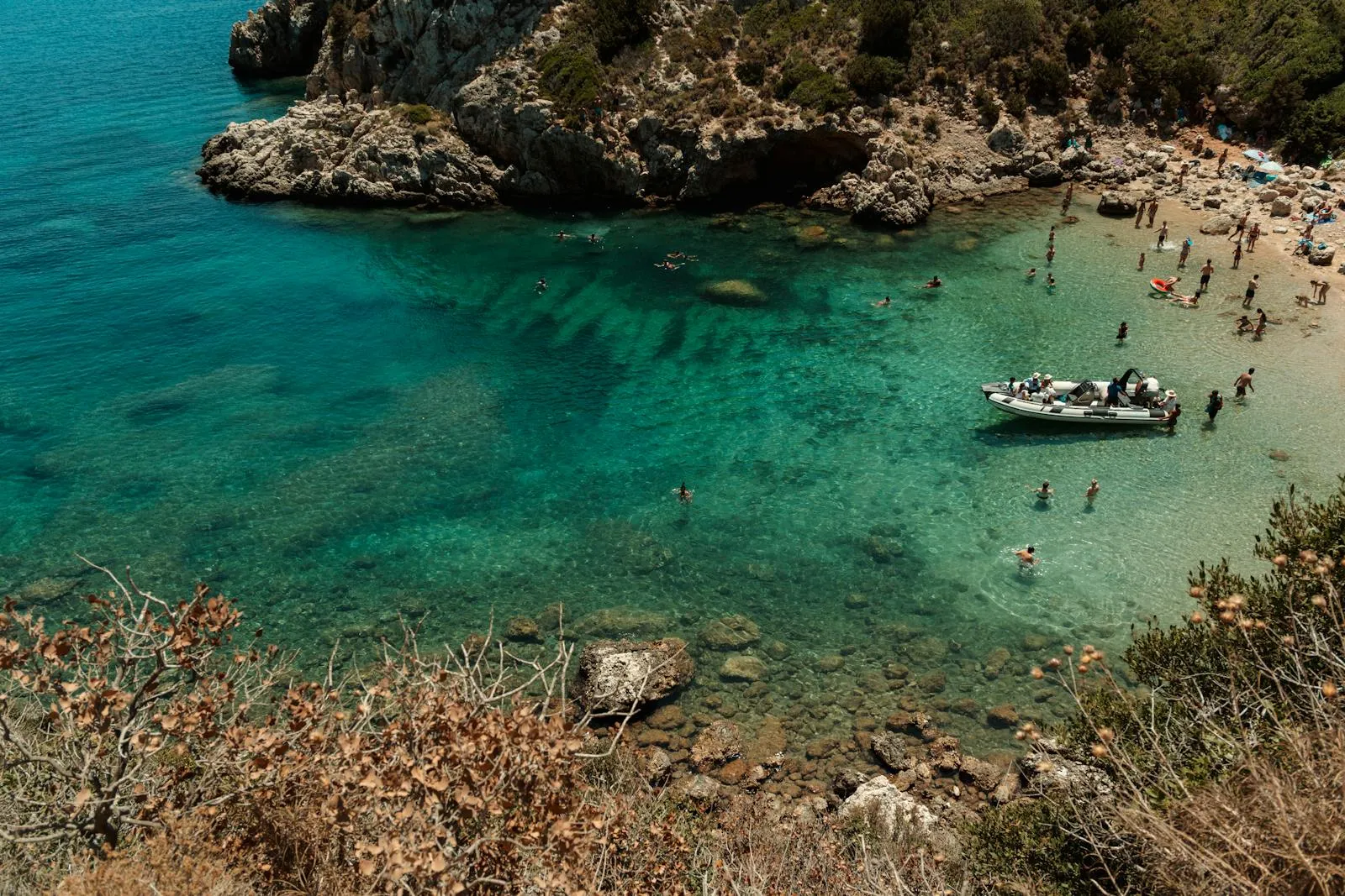 Clear Shallow Waters with Boats Near the Rocky Shoreline