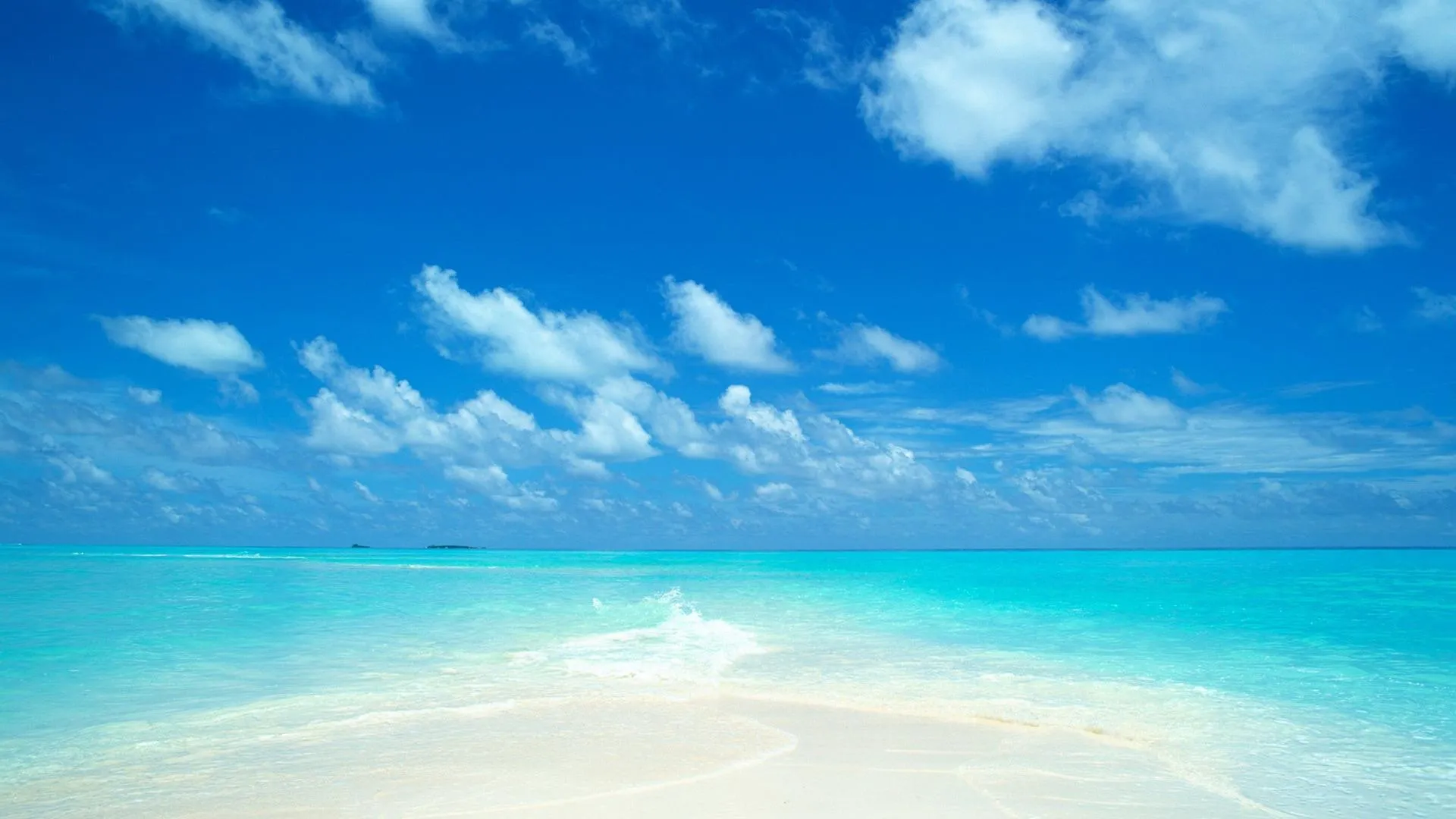 Clear Sunny Skies over Calm Blue Ocean and Soft Sand