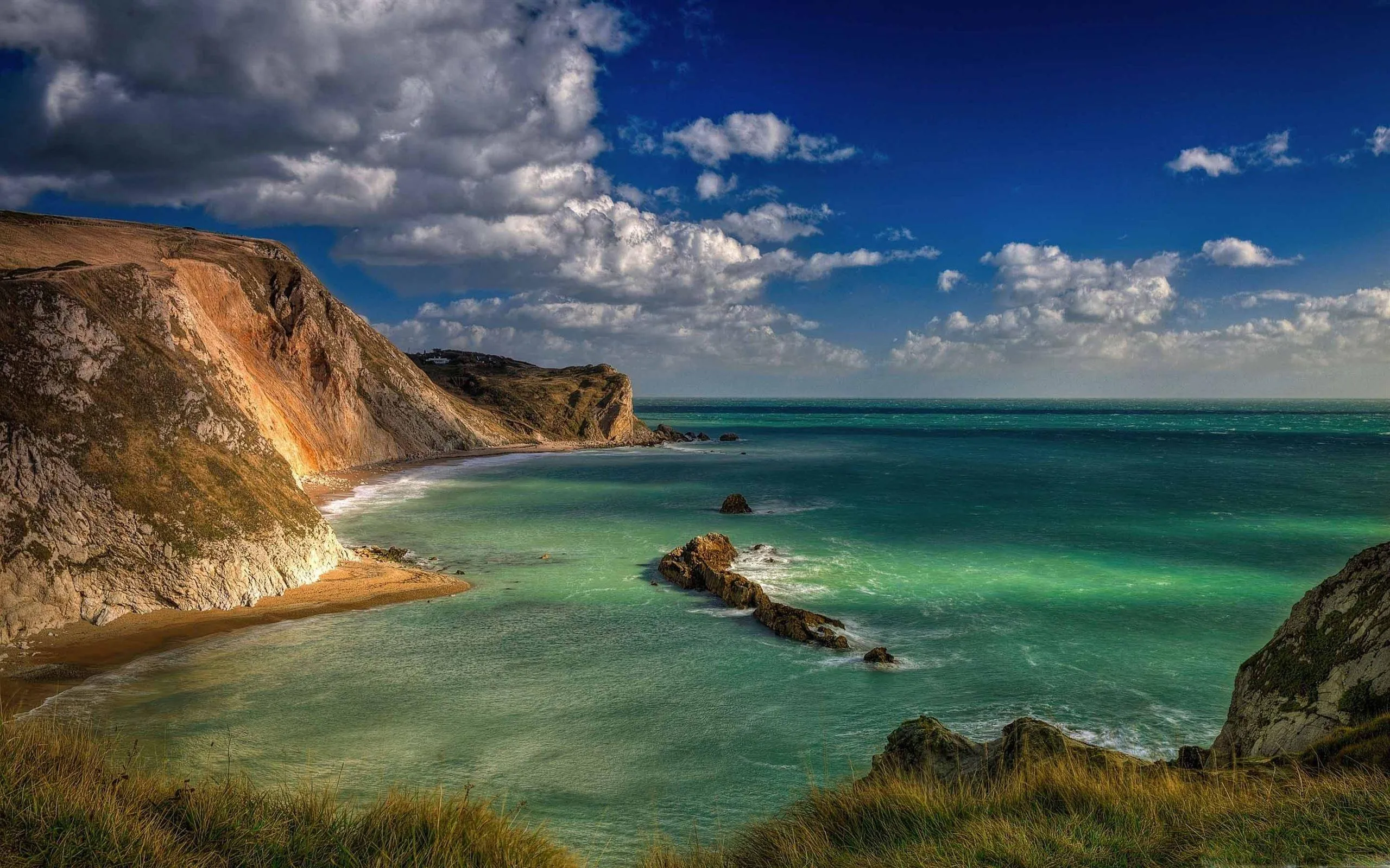 Cliffside Beach with Turquoise Water and Cloudy Sky