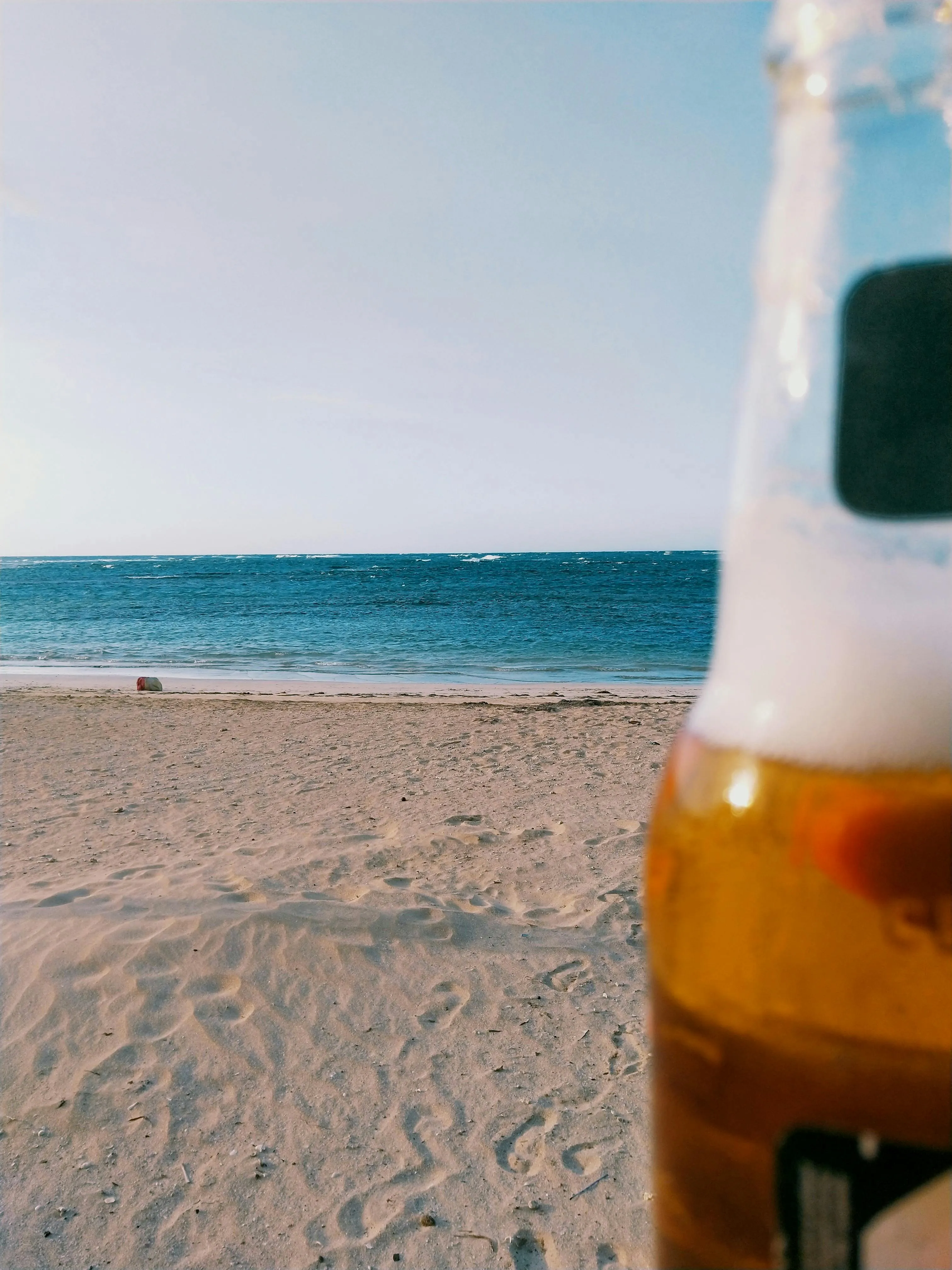 Cold Beer Bottle Close to the Beach and Blue Water View