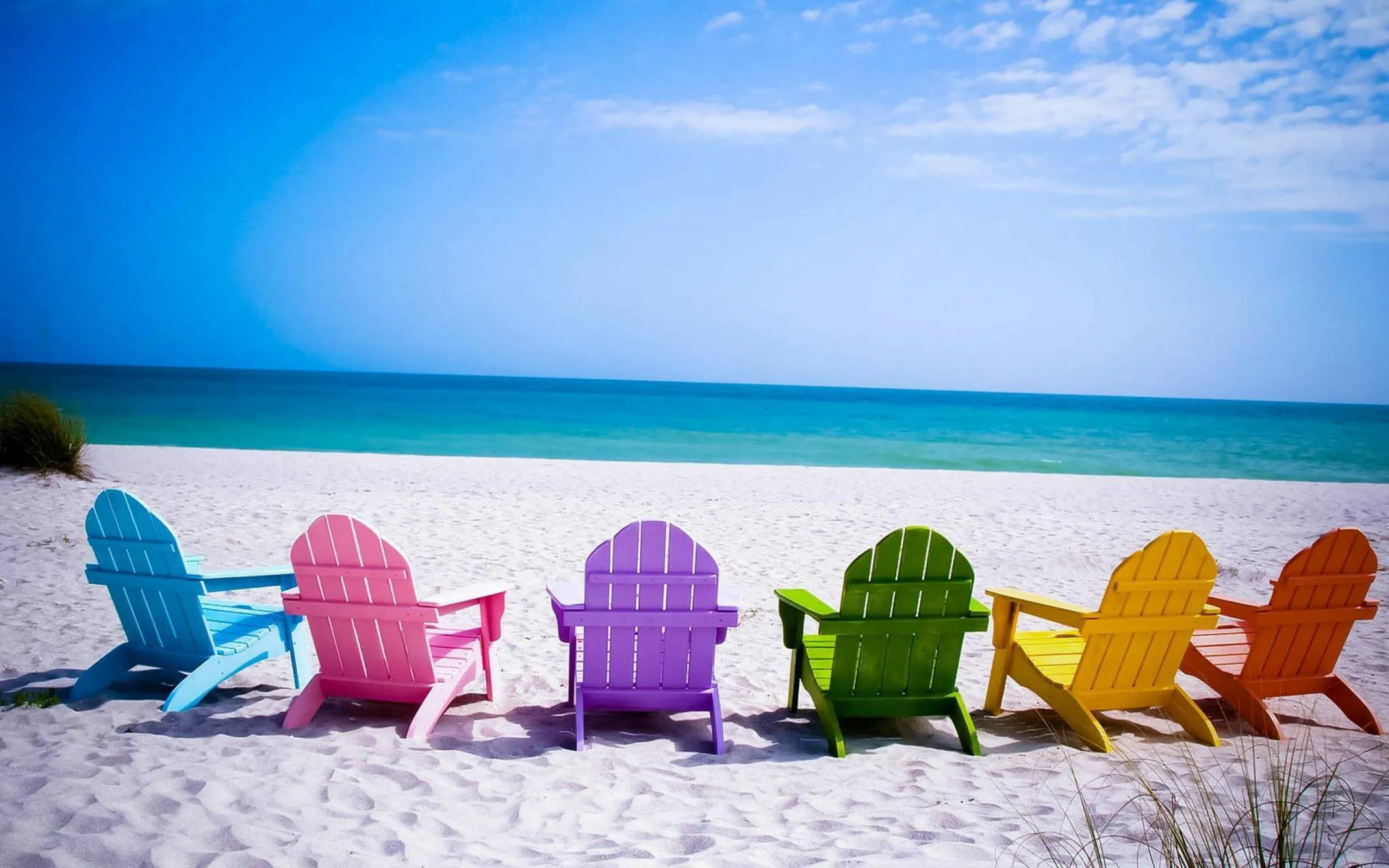 Colorful Chairs Lined Up Facing the Calm Blue Ocean and Sky