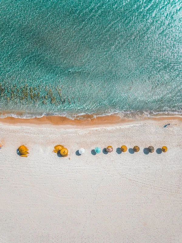 Colorful Umbrellas Lined Up on a White Sandy Beach Top View