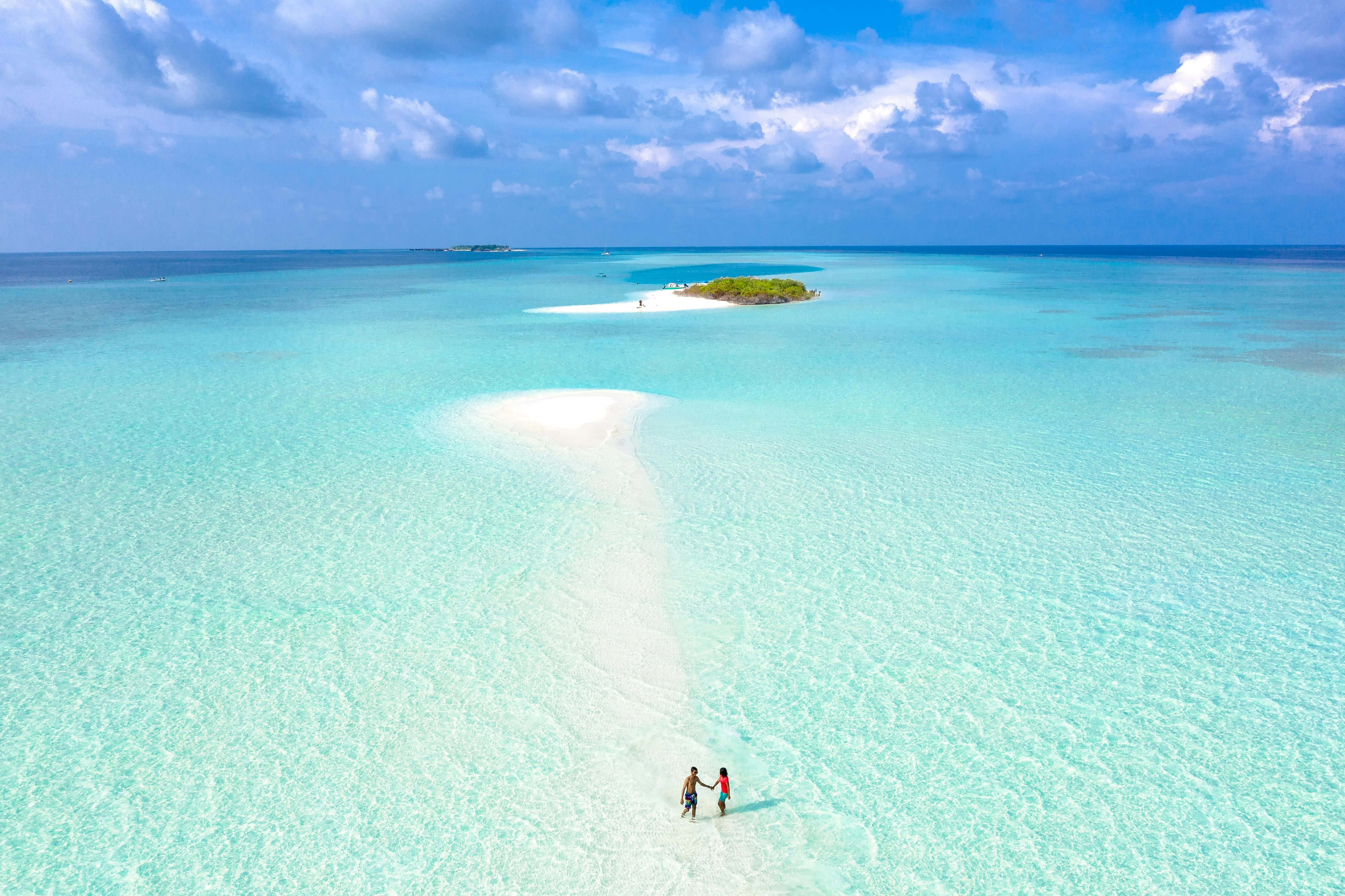 Couple Standing in Shallow Blue Water Near a Small Island