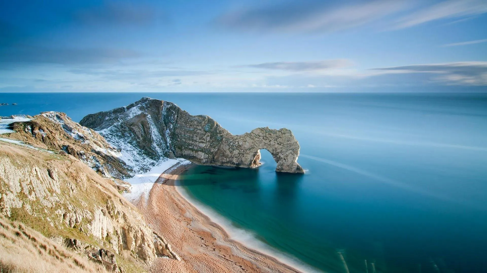 Curved Beach Along Rocky Cliffs with Clear Blue Green Sea