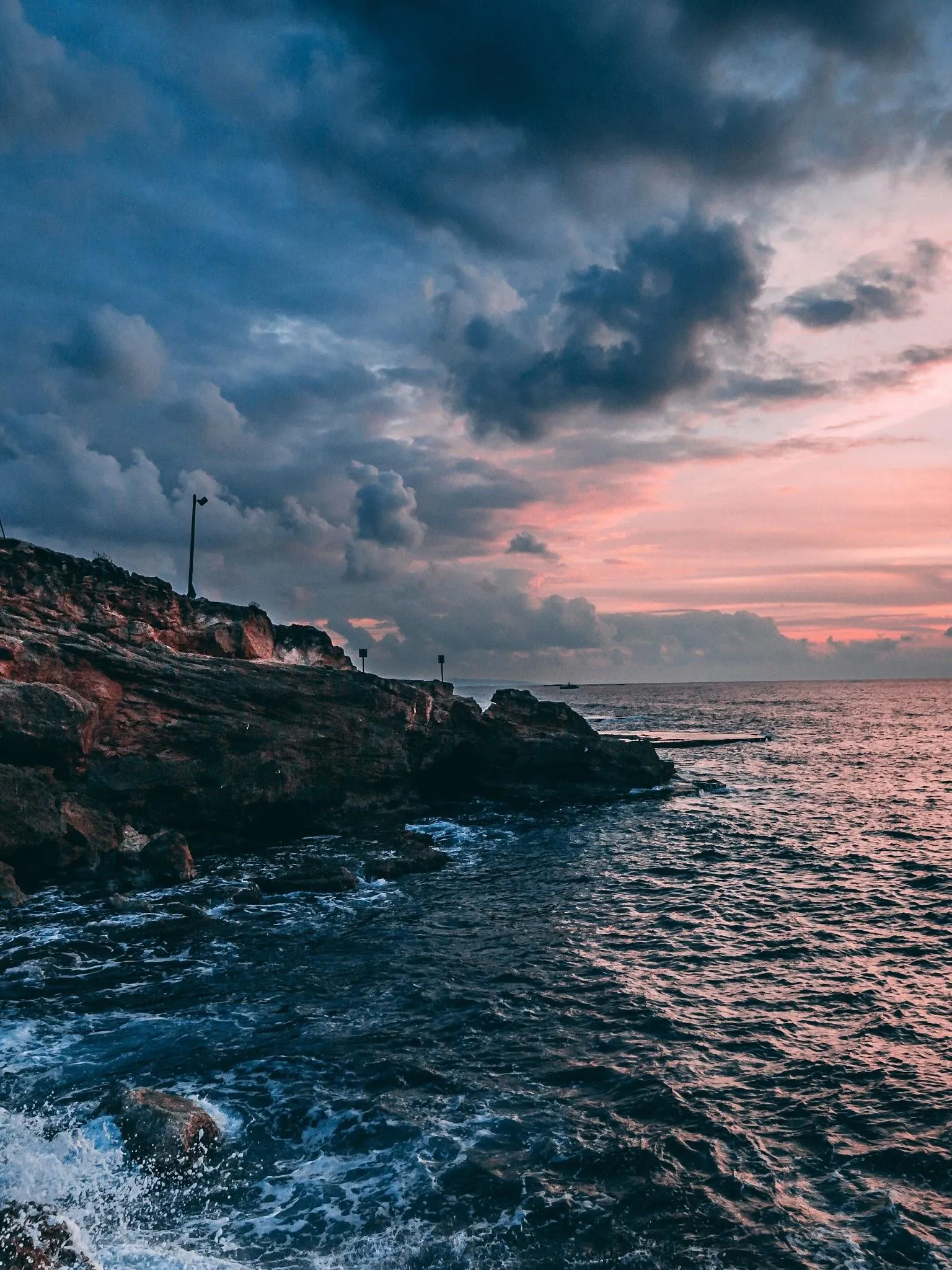 Dark Rocky Coast with Sunset Glow and Cloudy Sky Wallpaper