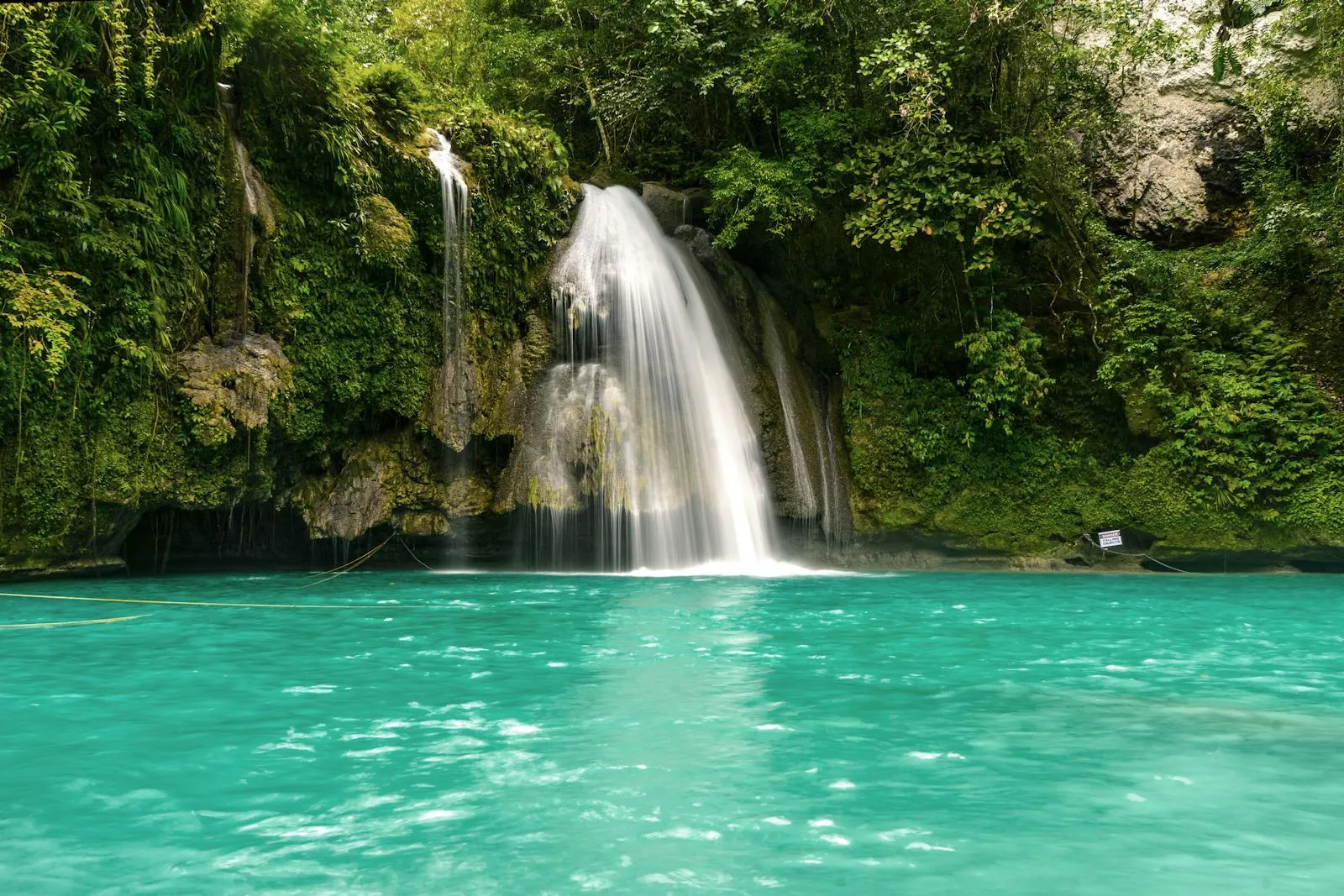 Emerald Waterfall Flowing into a Crystal Clear Pool