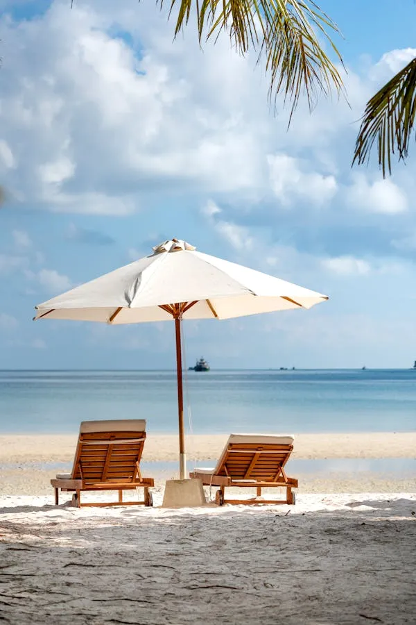 Empty Lounge Chairs Under a White Umbrella on the Beach