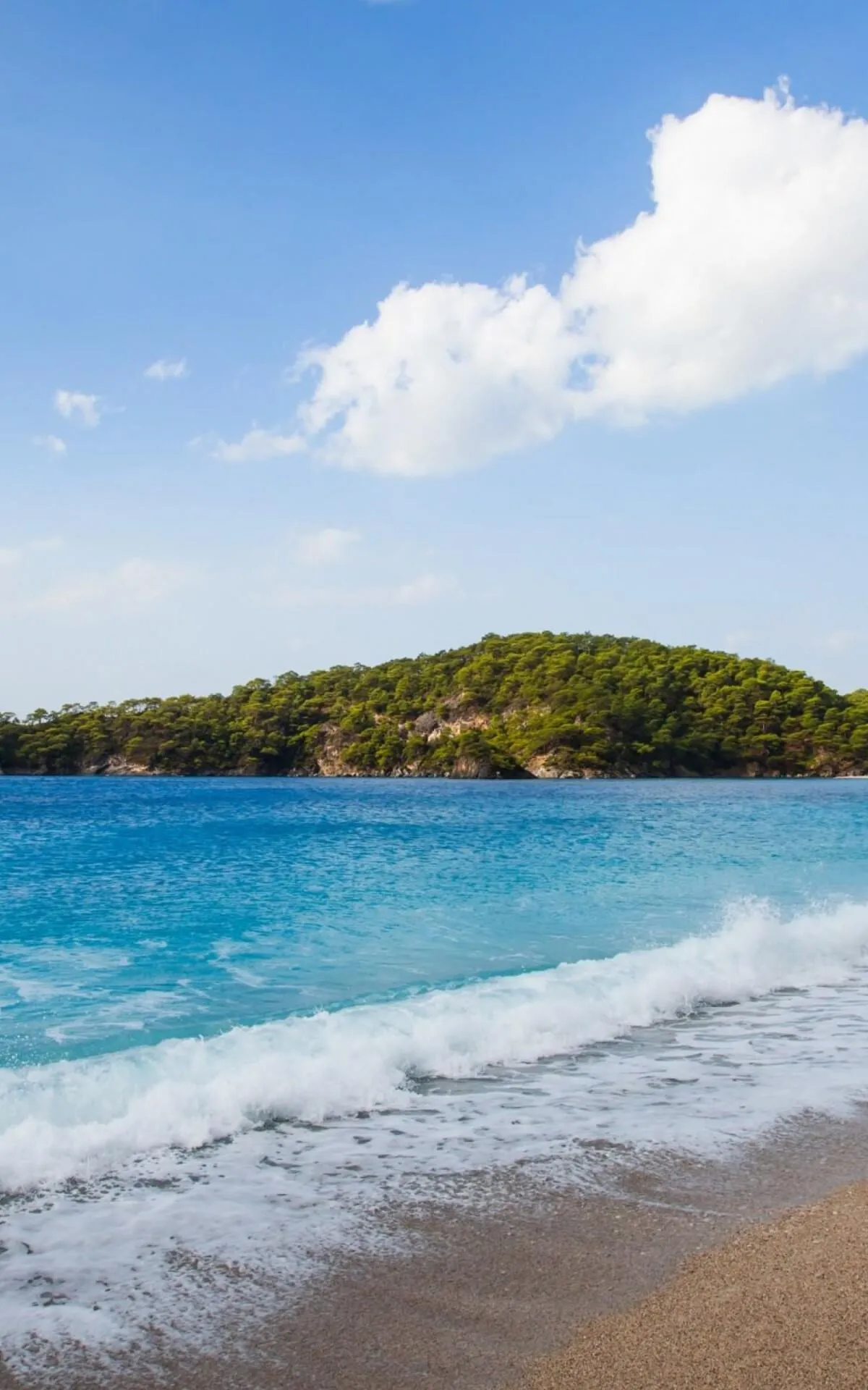 Gentle Waves Meeting Sandy Beach Under Bright Blue Sky