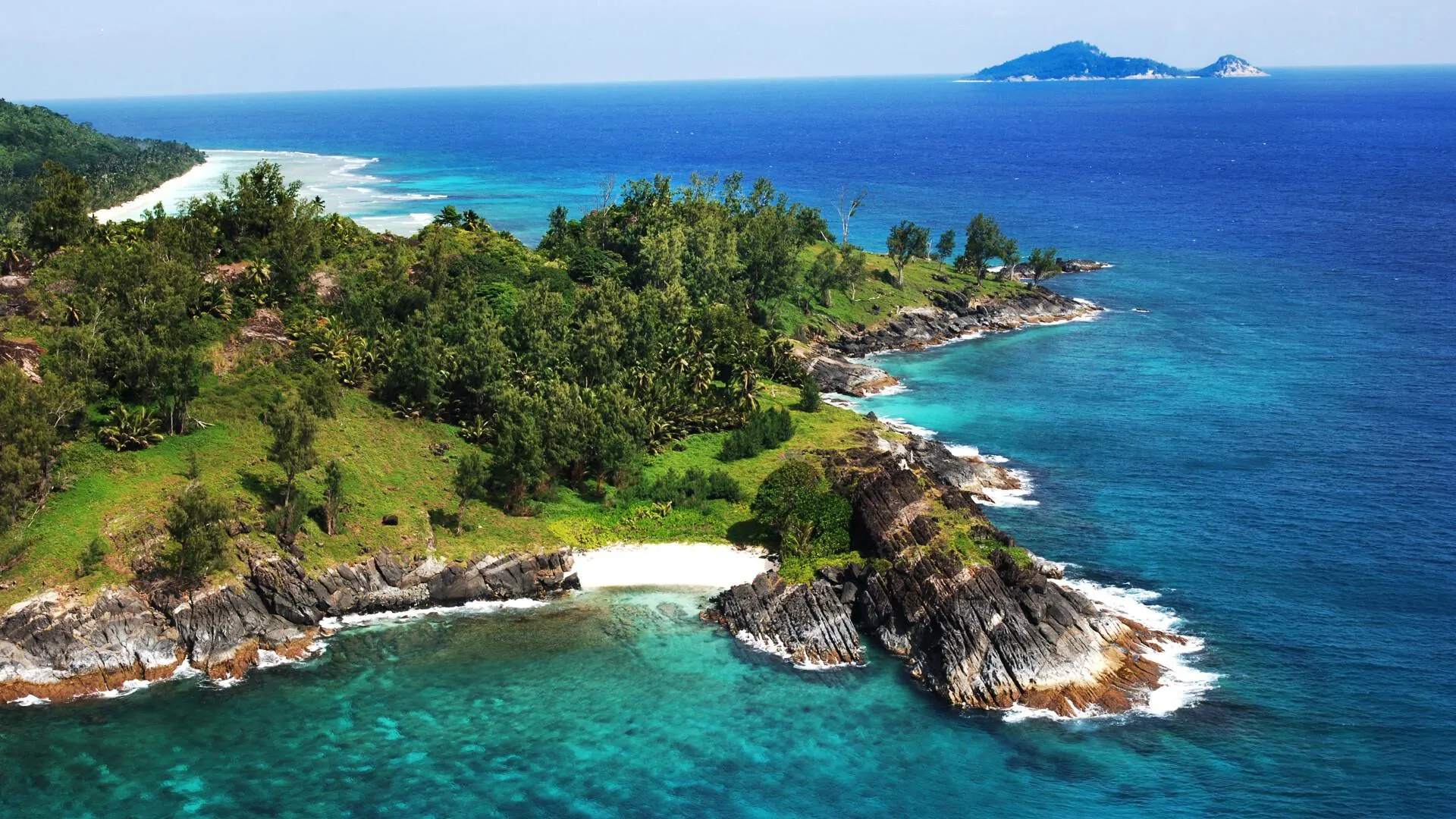 Green Island with Rocky Coast in Clear Blue Sea Wallpaper