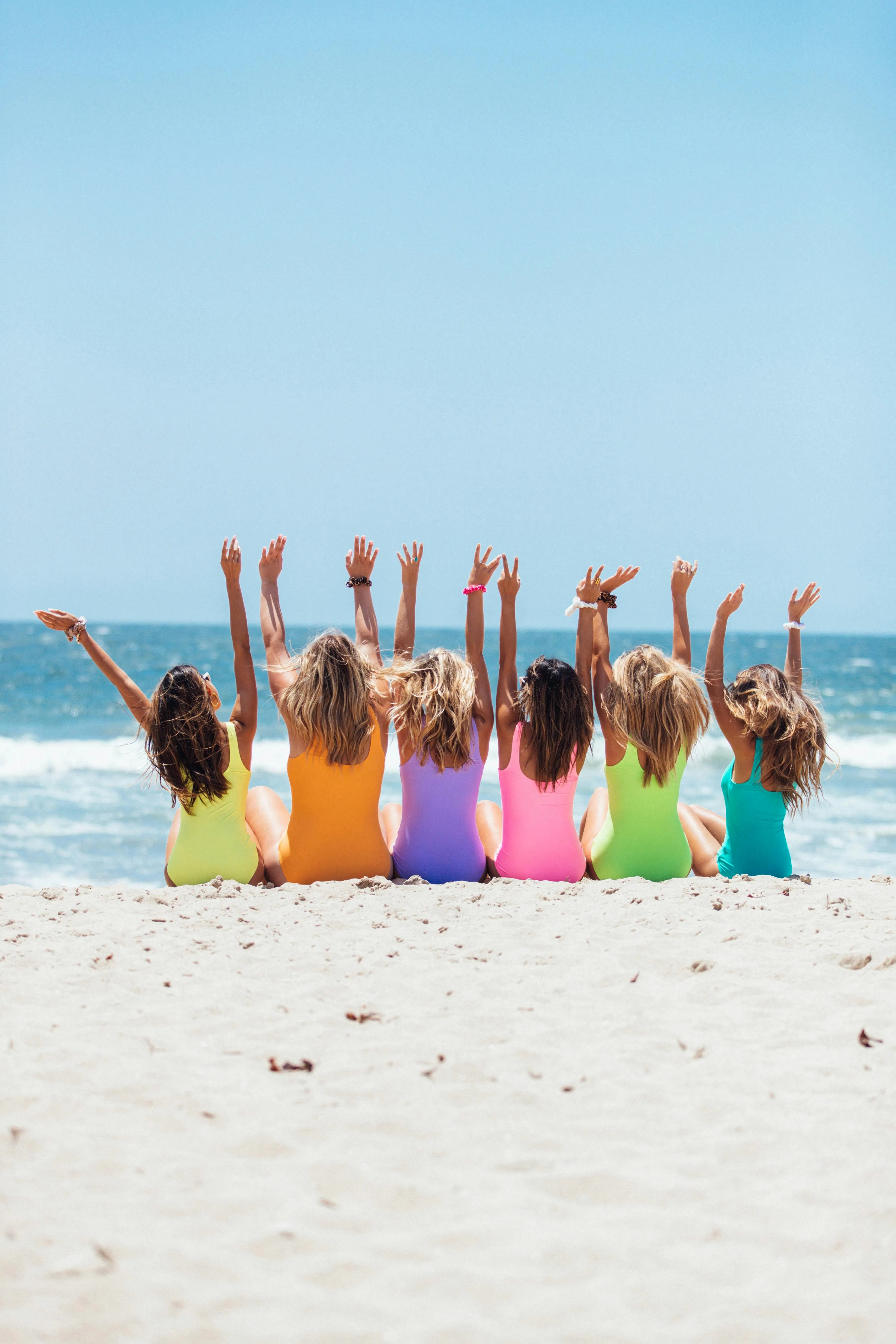 Group of Kids Raising Hands Happily on a Bright Sandy Beach