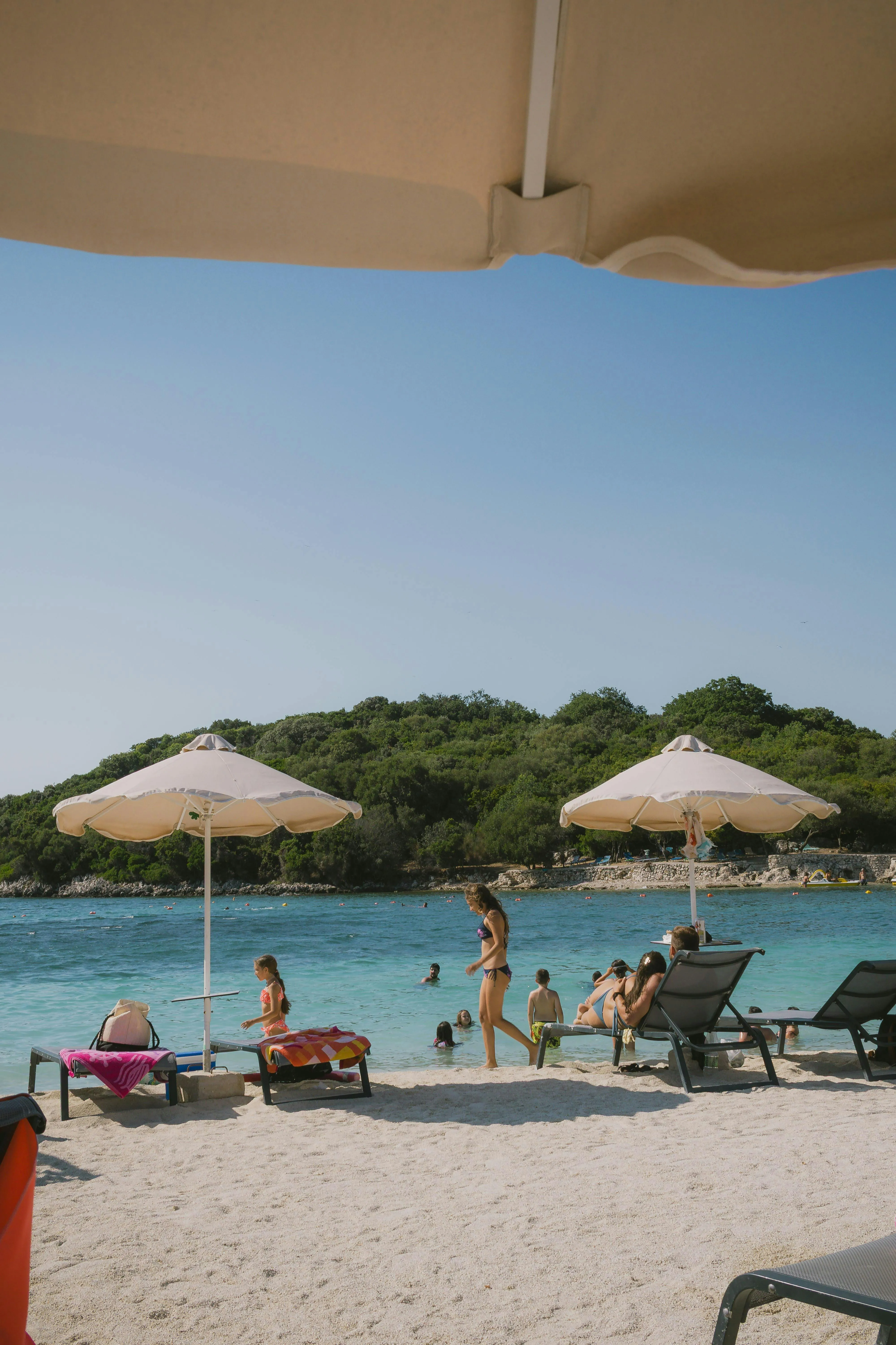 Guests Enjoying the Beach Under Umbrellas Free Wallpaper