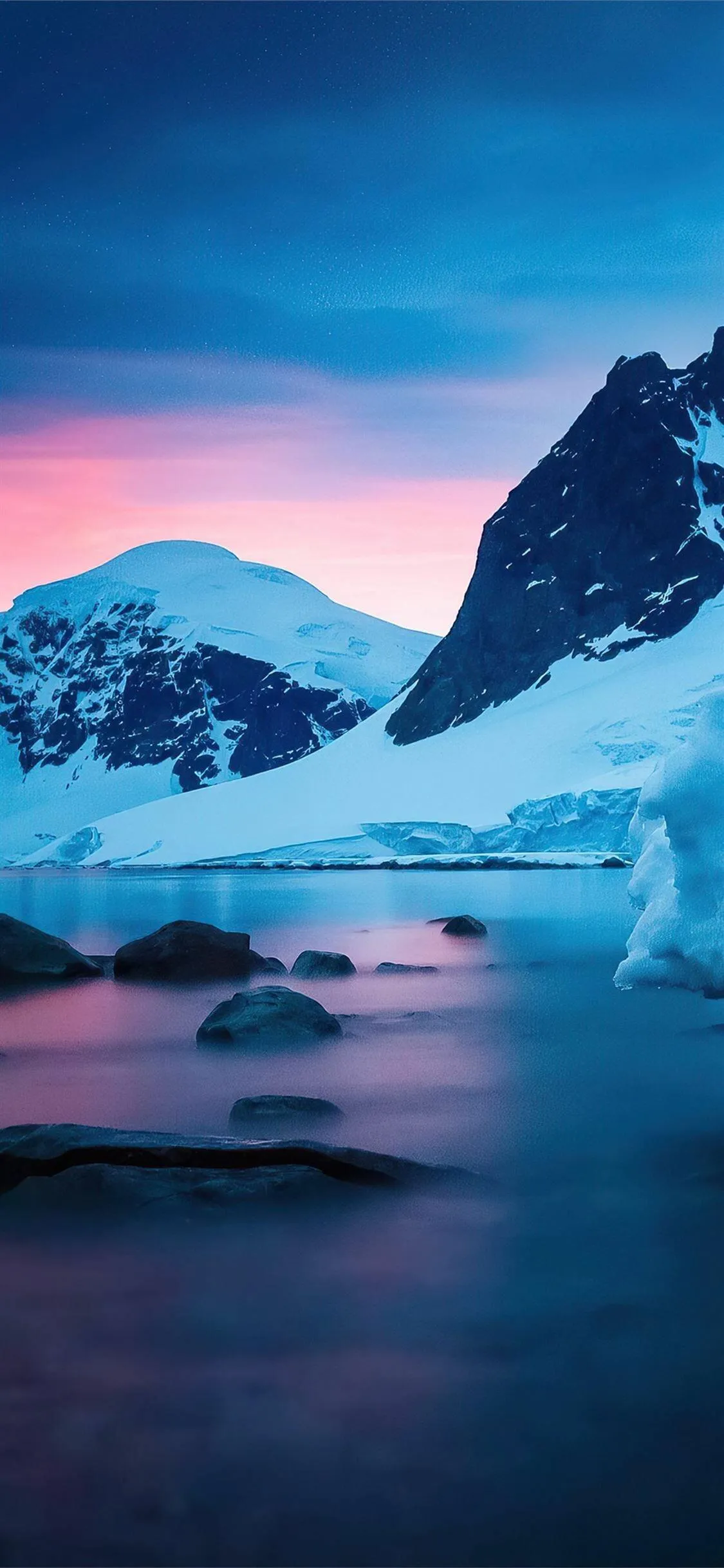 Icebergs Floating Near Dark Rocks Under a Glowing Blue Sky