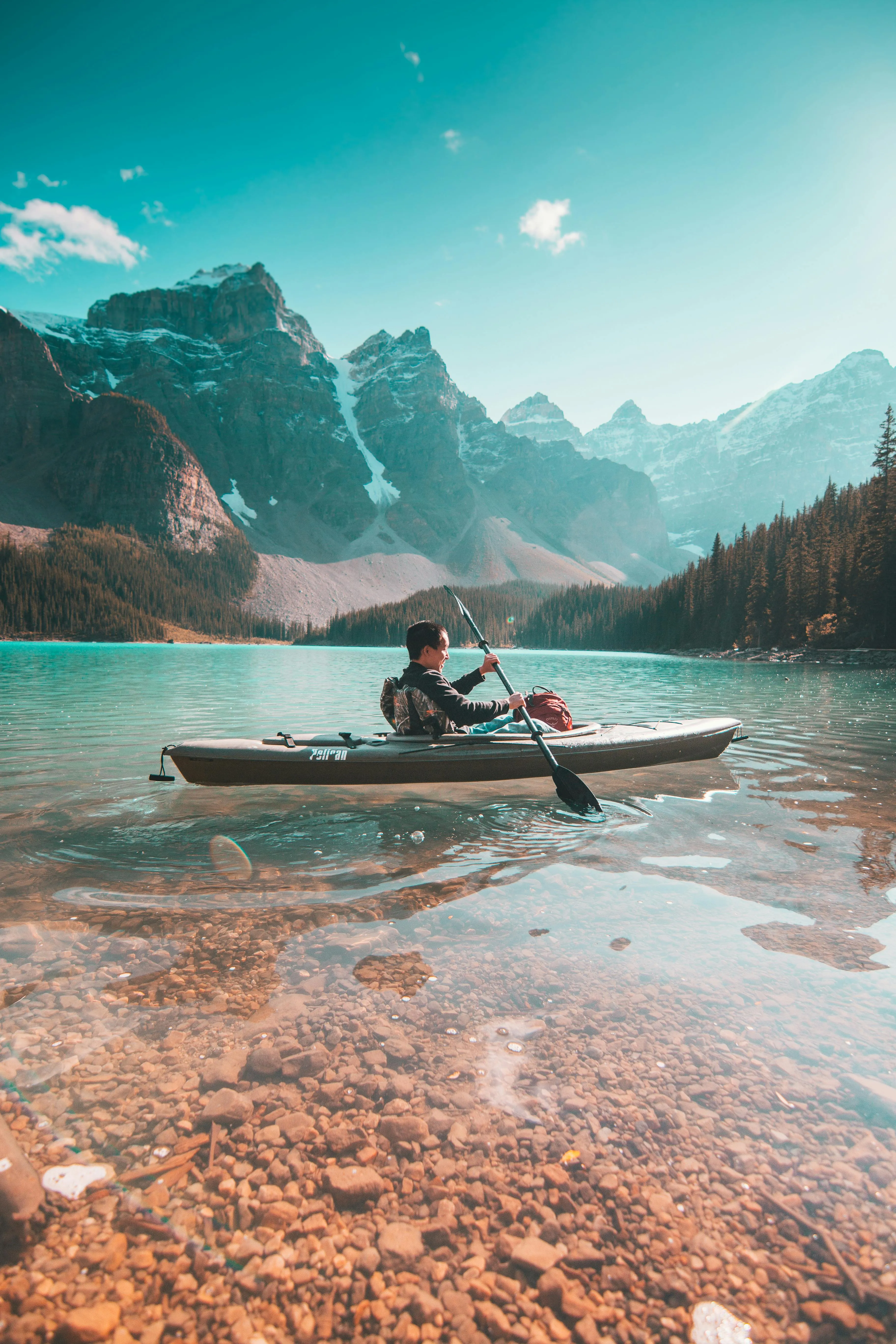 Kayaker on a Calm Lake with Mountains and Clear Blue Sky