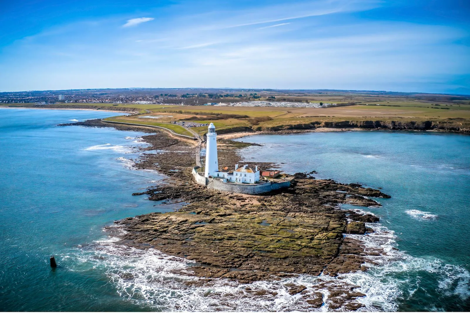 Lighthouse Perched on Rocky Coastline Under a Blue Sky