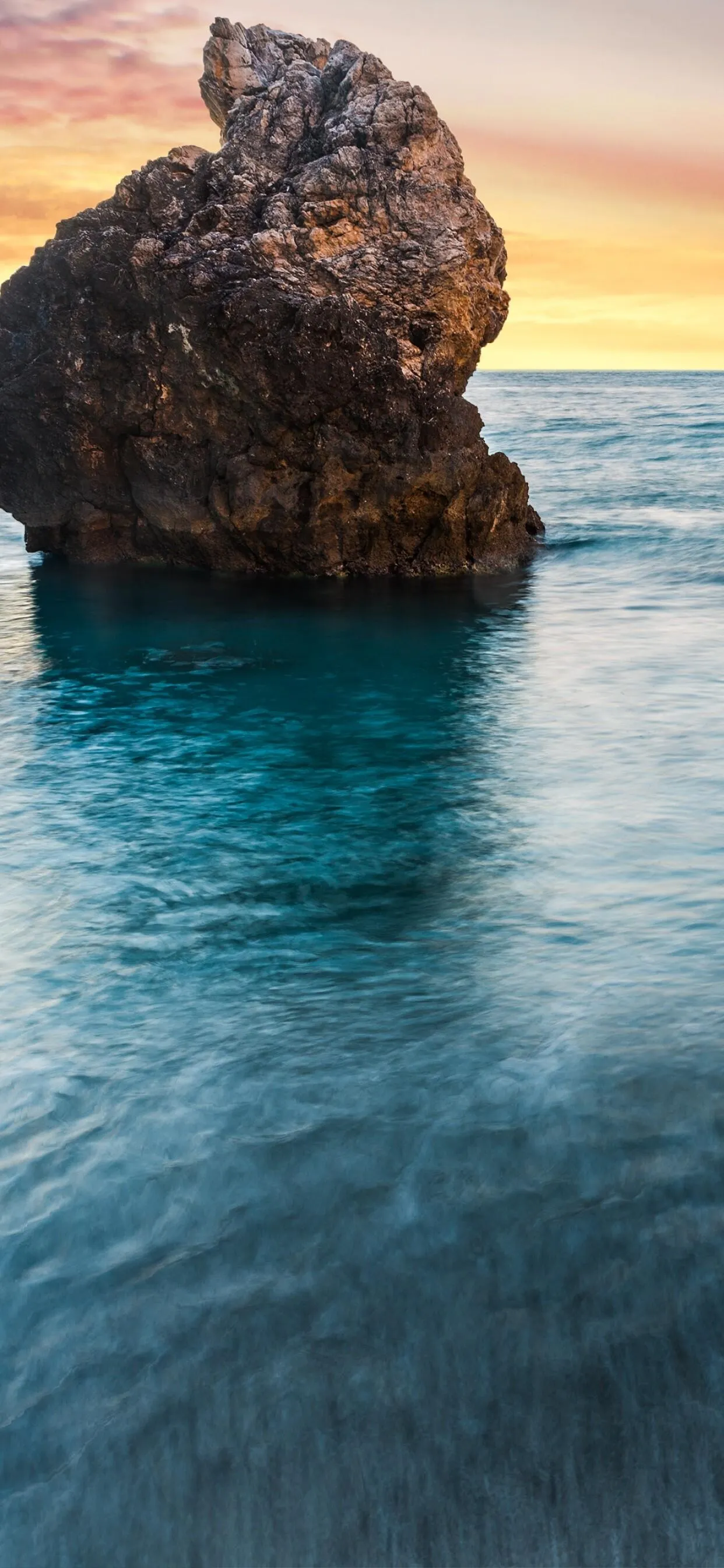 Lone Rock Formation Standing in a Clear Calm Ocean Surface