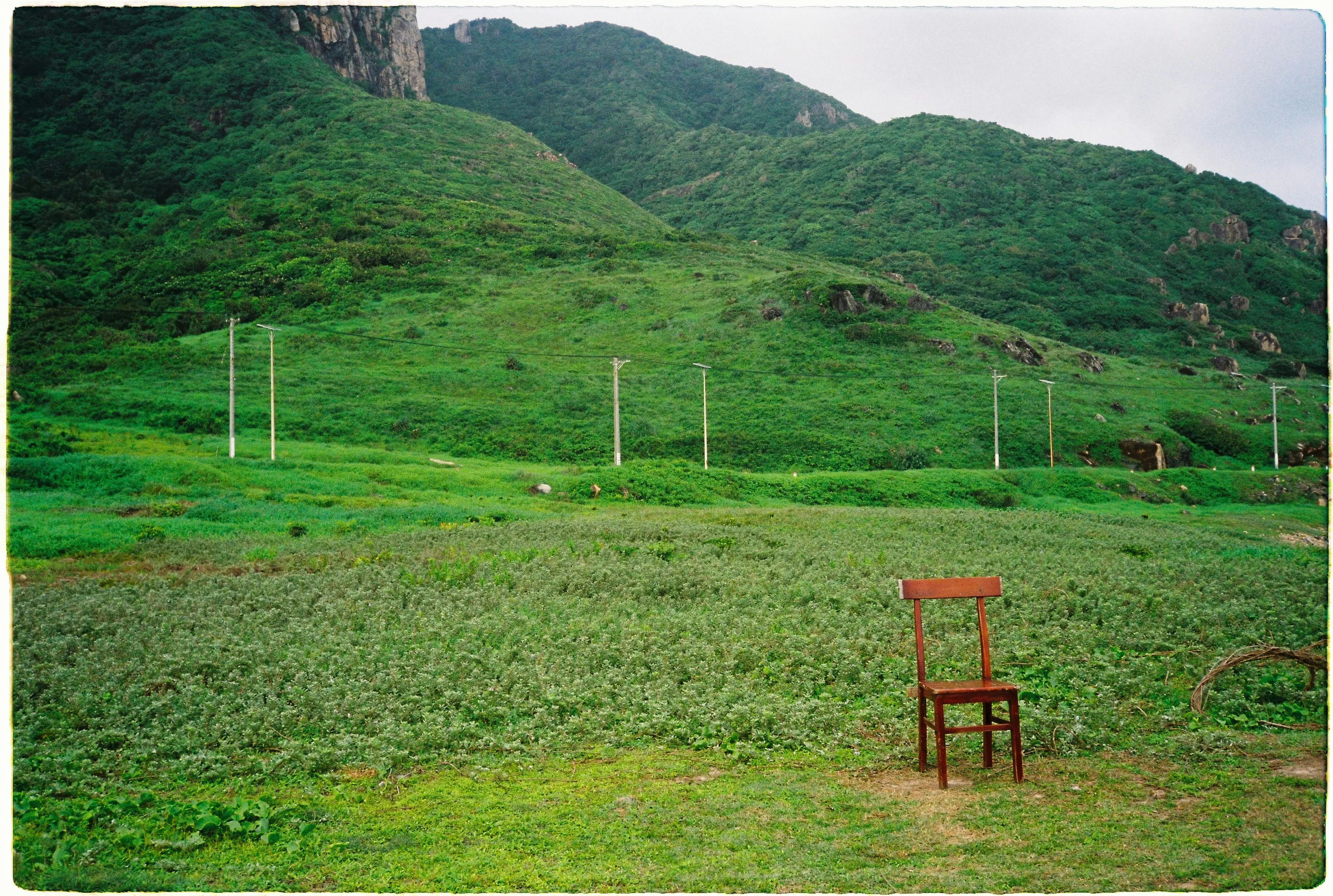 Lonely Chair Standing on Grass Near Lush Green Mountains