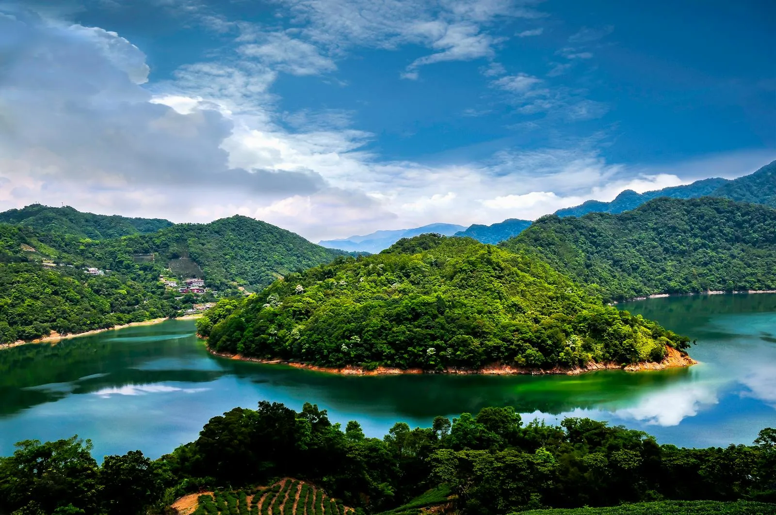 Lush Green Island Surrounded by Calm Blue Waters and Hills
