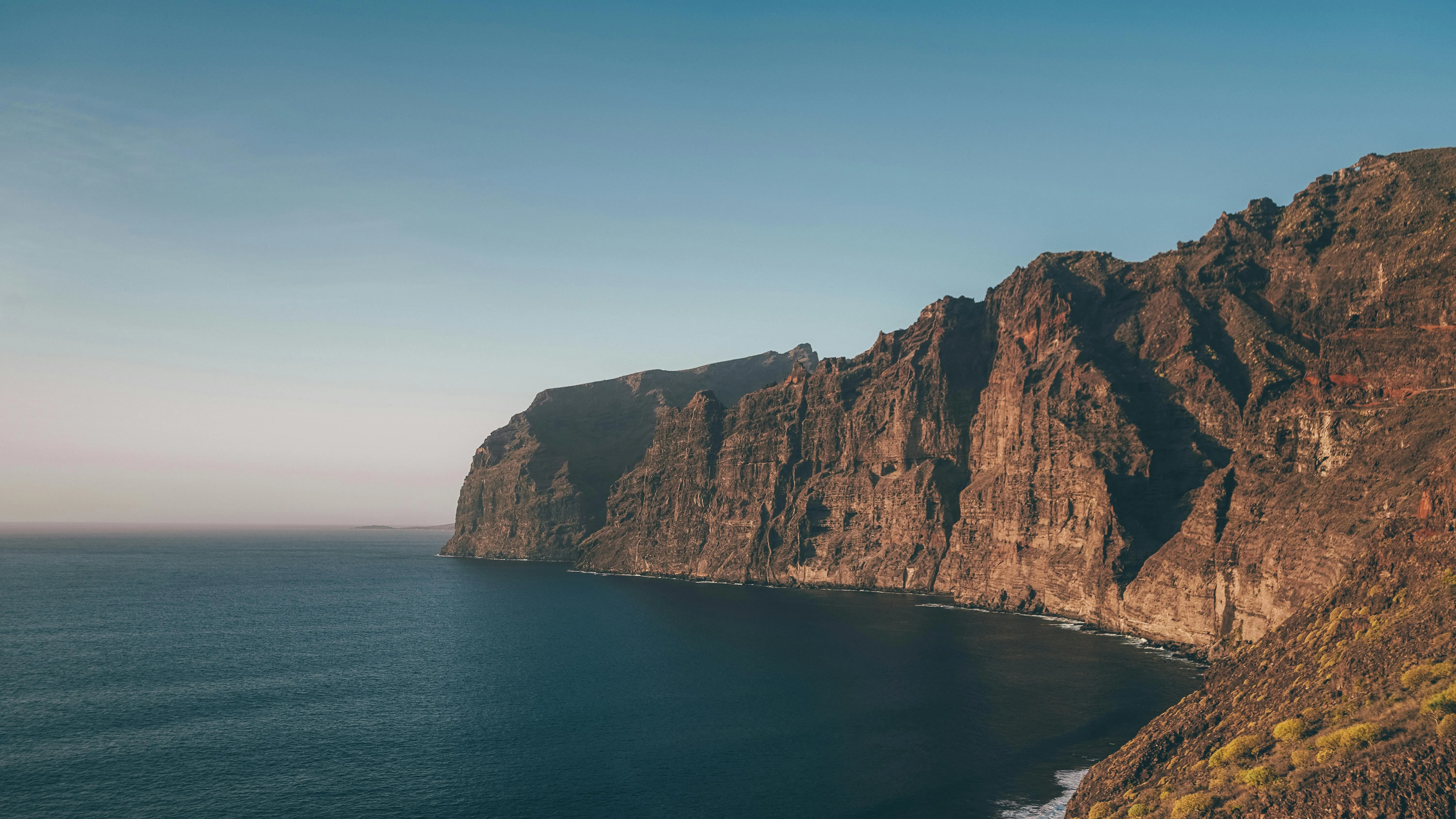 Massive Cliffs Rising Above a Calm Crystal Blue Seashore