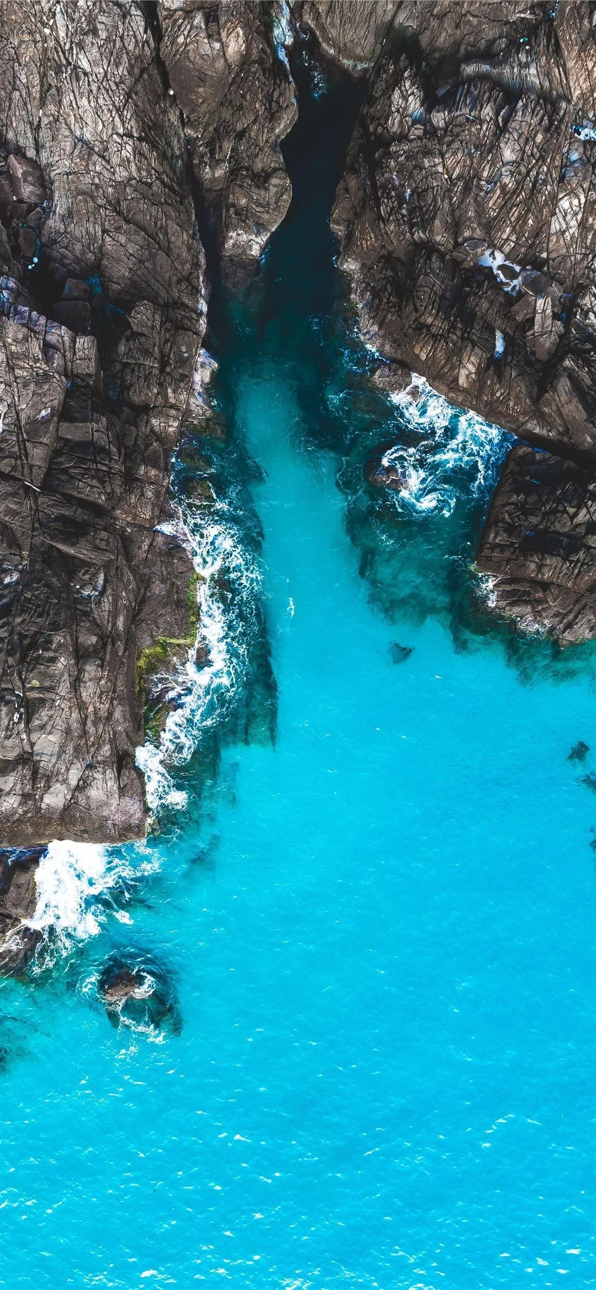 Narrow Blue Lagoon Between Tall Rocky Cliffs and Clear Water