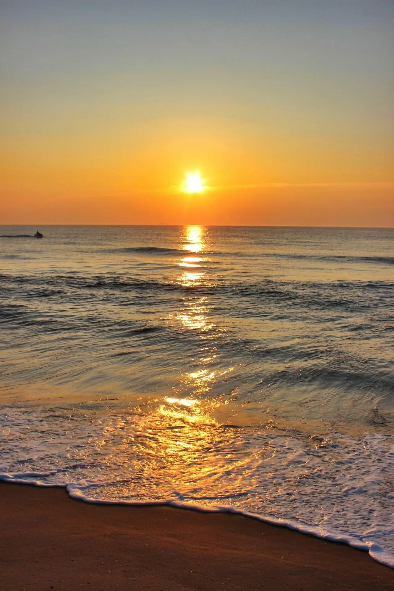 Orange Sun Setting on Calm Ocean Waves at a Quiet Beach