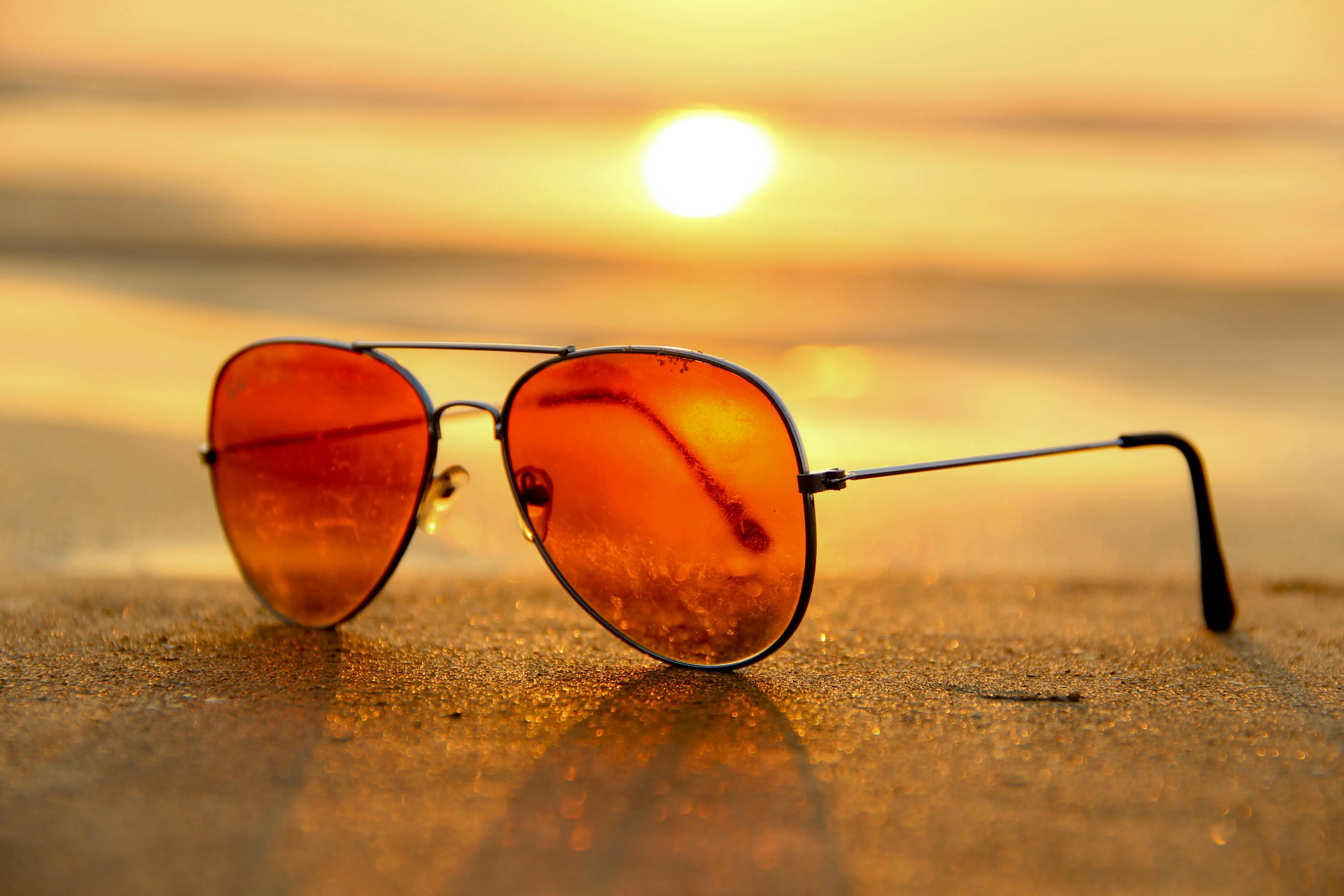 Orange Sunglasses on Sandy Beach at Sunset Golden Hour