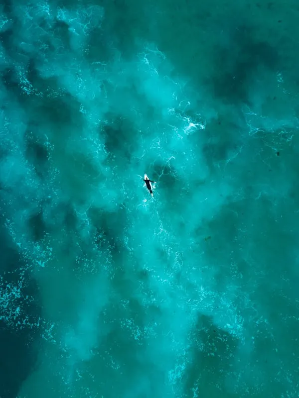 Paddleboarder Gliding Across Deep Turquoise Ocean Wallpaper