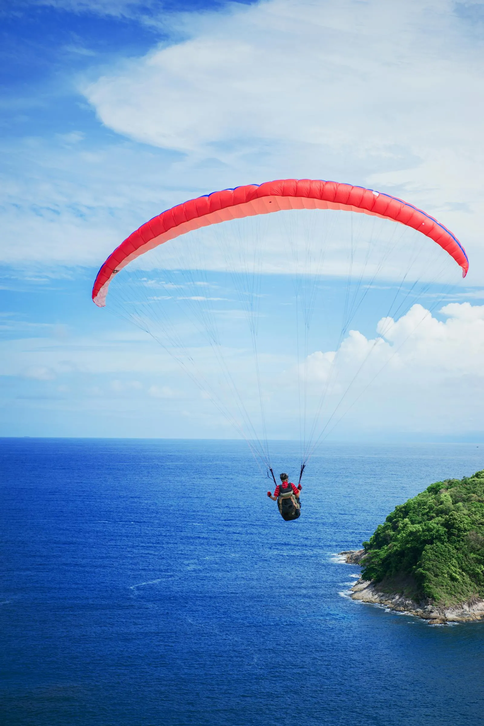 Paraglider over the Blue Sea Near a Green Island Wallpaper