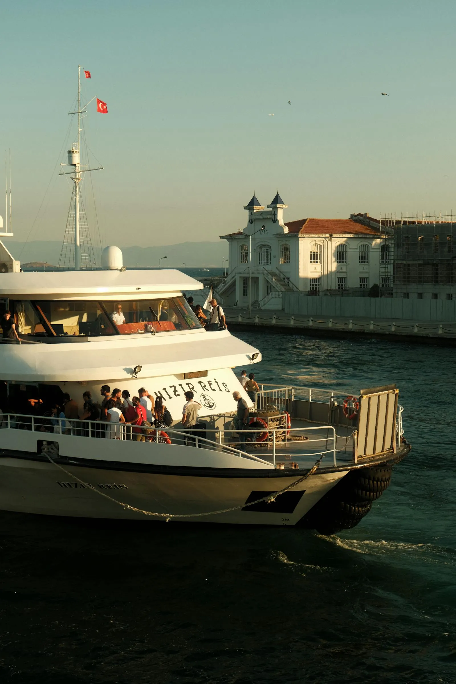 Passenger Boat Cruising Near Coastal Buildings Wallpaper