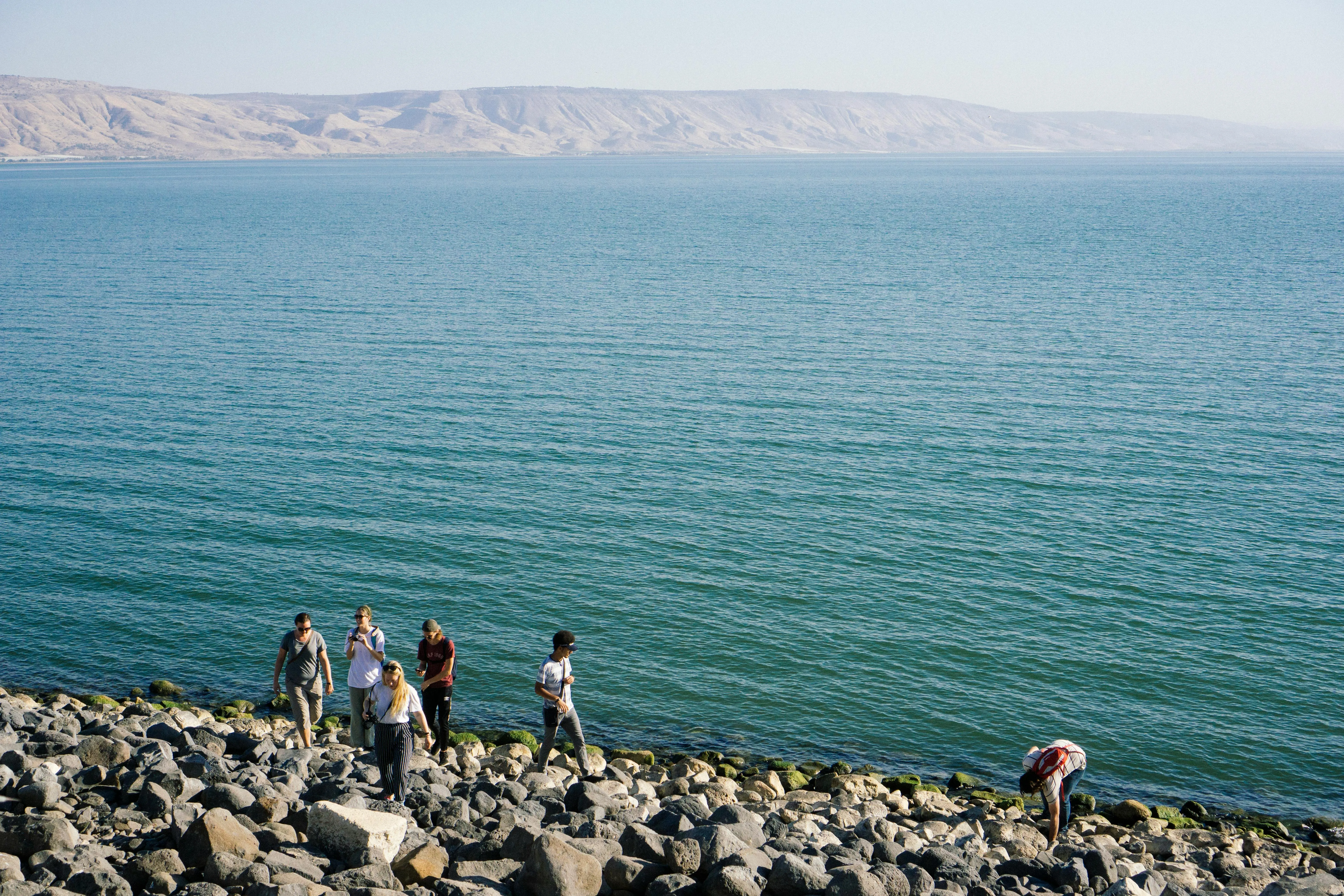 People Stand on a Rocky Coast Under the Sunlight Wallpaper