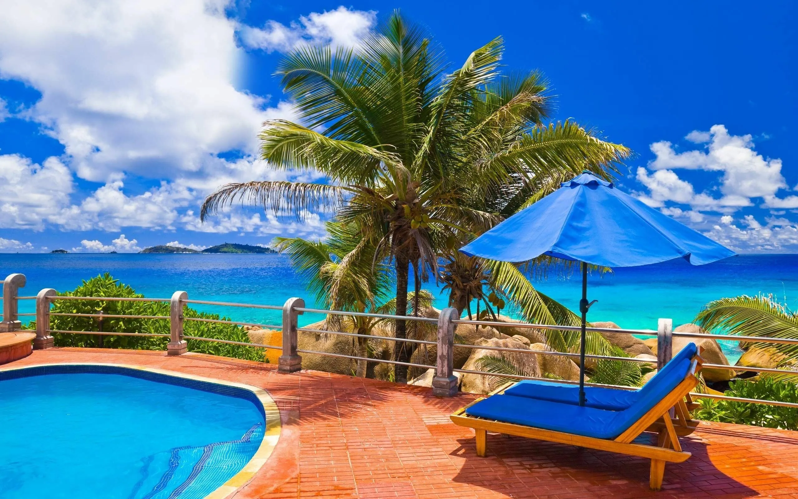 Poolside Lounge Chairs with Blue Umbrellas Near Ocean View