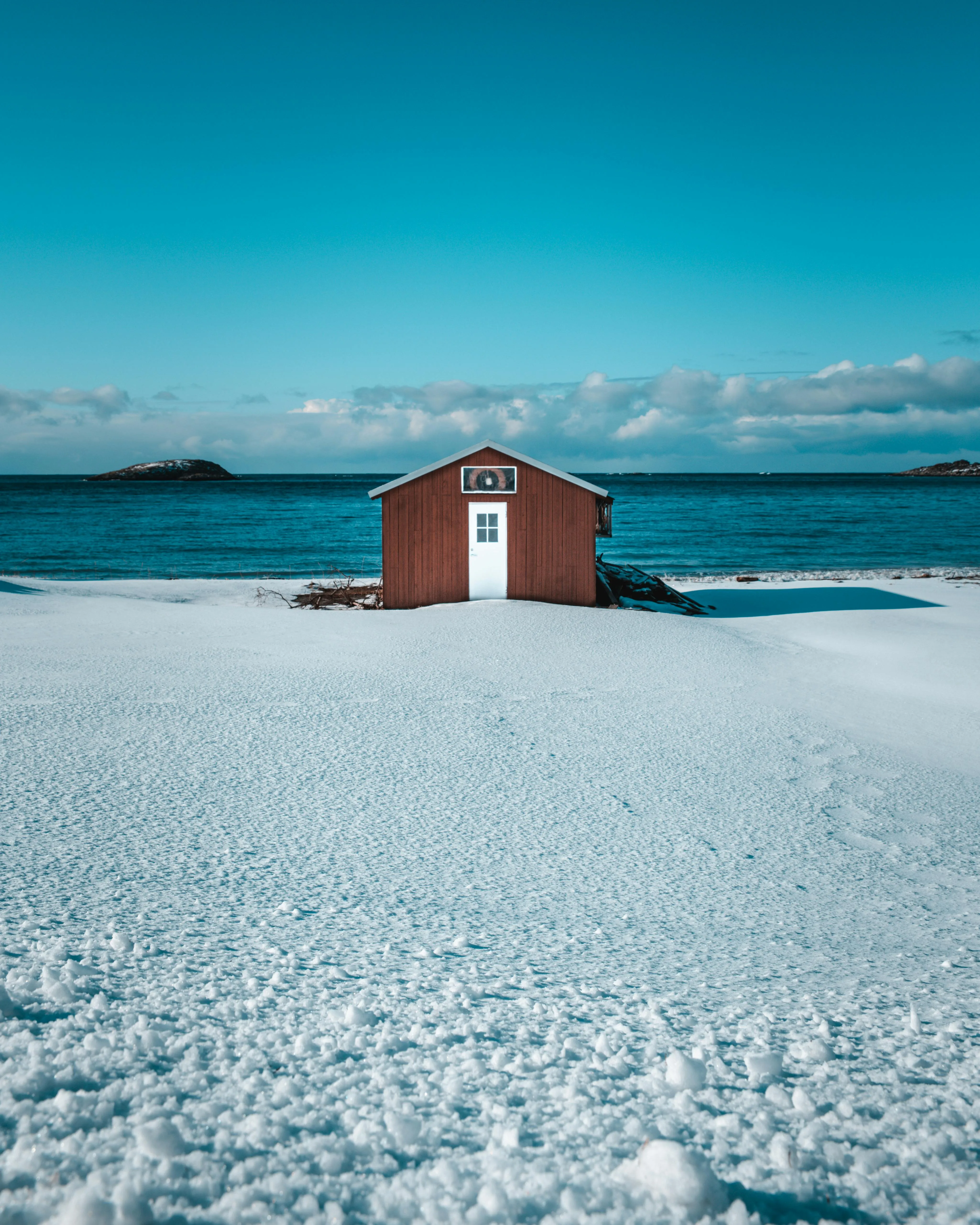 Red Cabin on Frozen Beach with Blue Sky Free Wallpaper