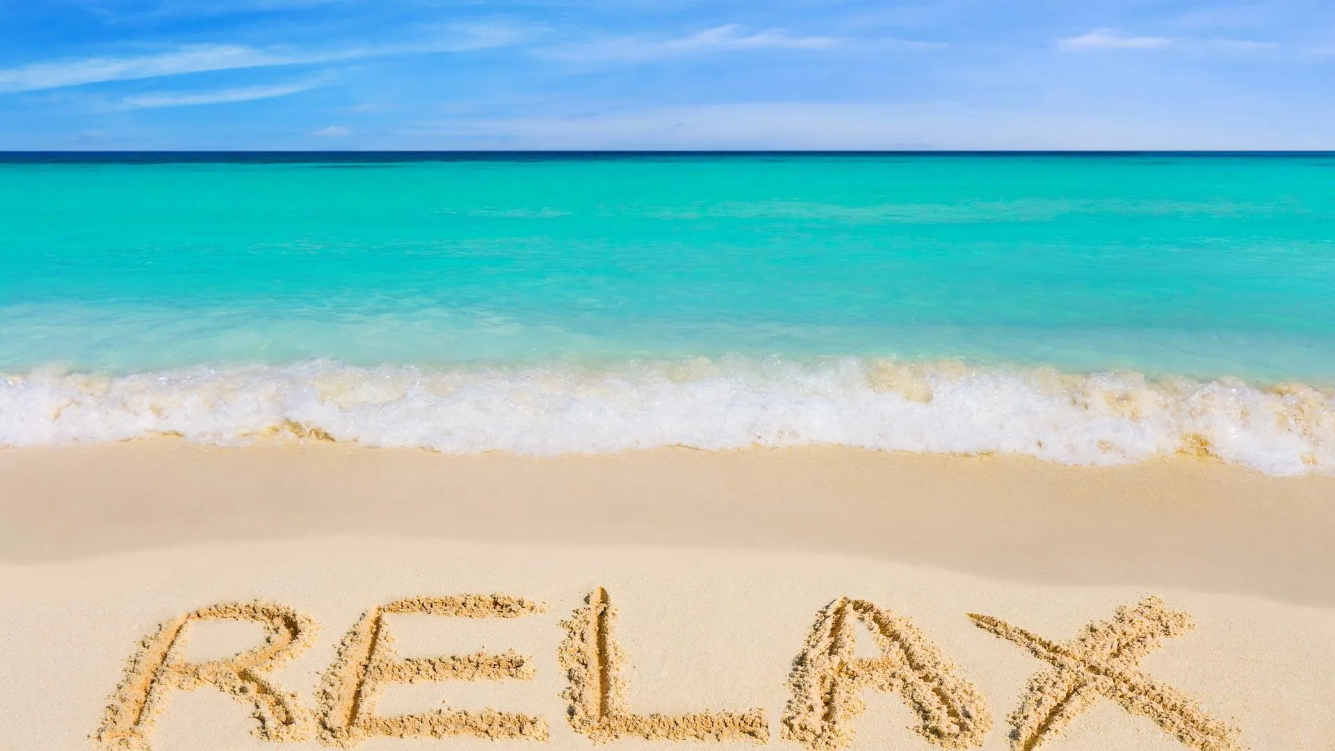 Relax Written in Sand on the Beach with Turquoise Blue Sea
