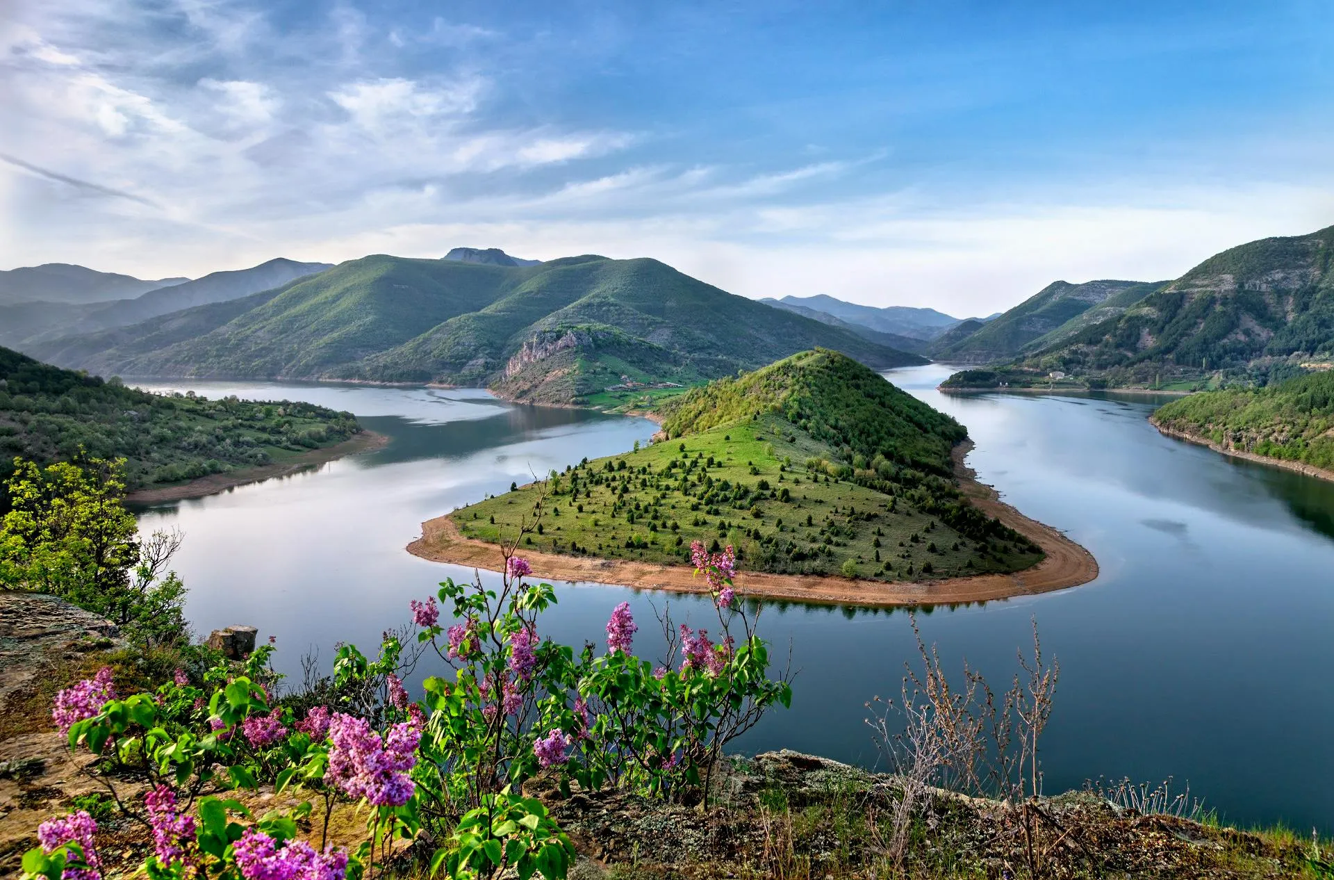 River Meets Hills Under Blue Sky Download Free Wallpaper