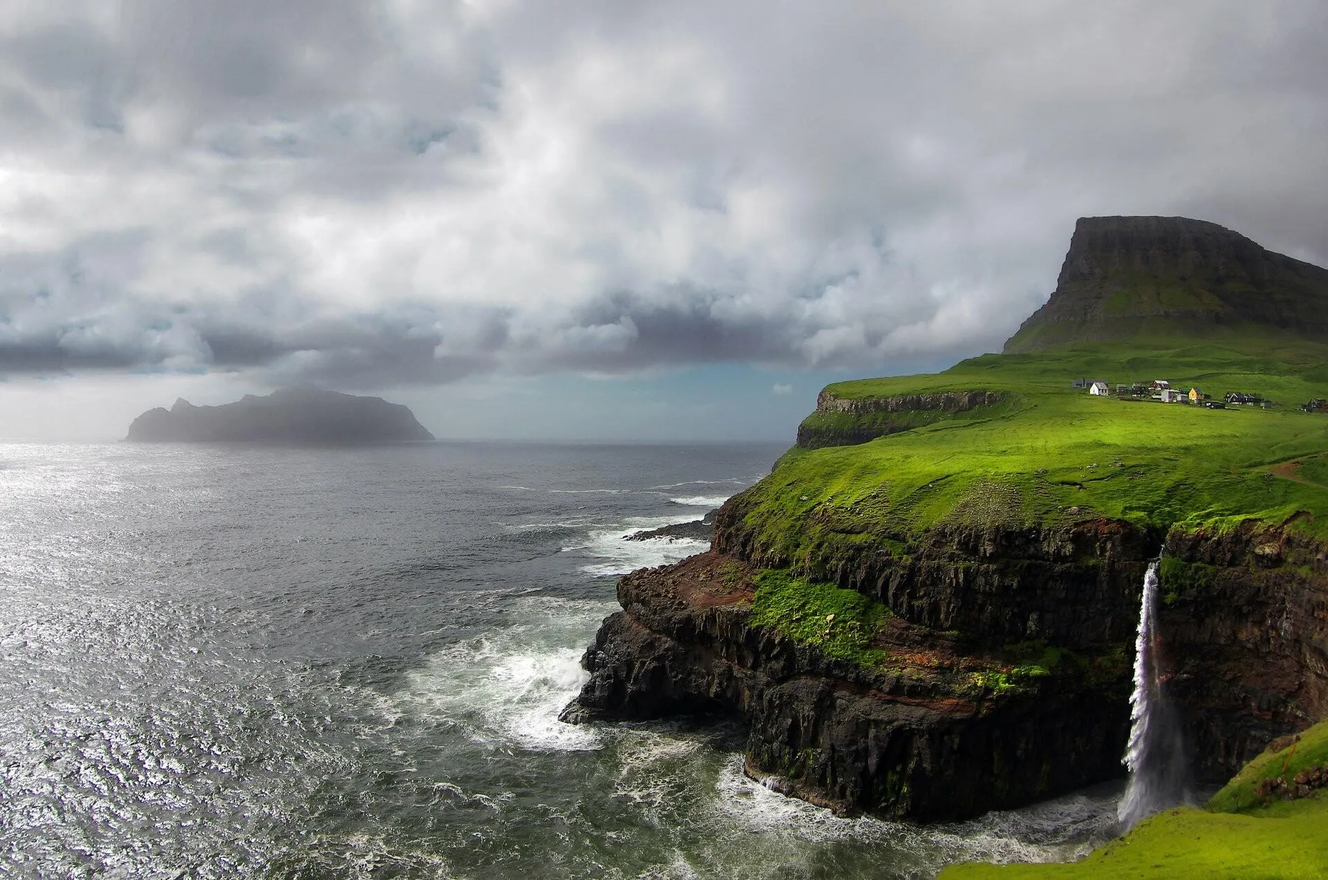 Rocky Green Cliffs Rising Above the Ocean Under Cloudy Skies