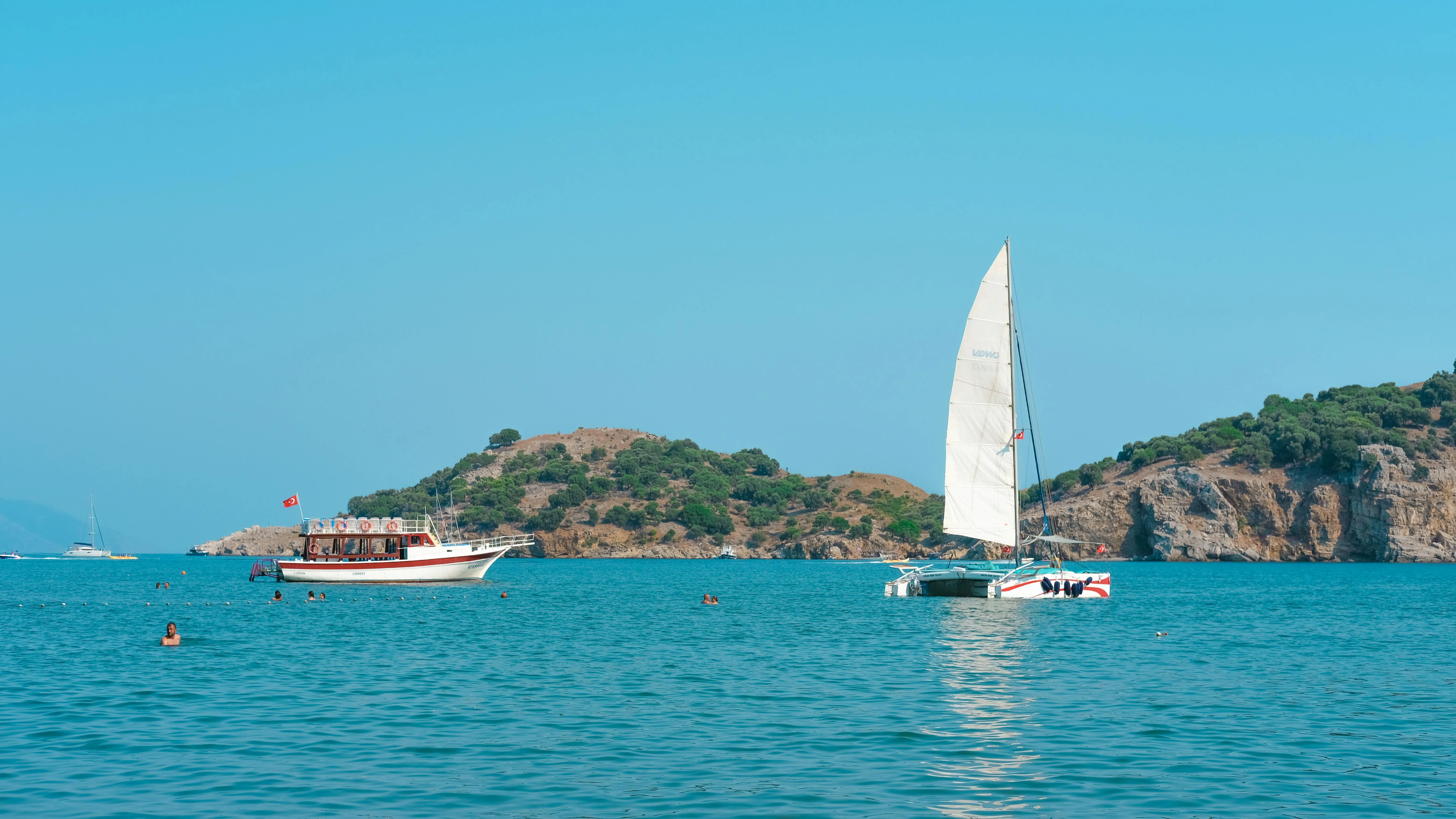 Sailboat Gliding in the Blue Ocean Near an Island Wallpaper
