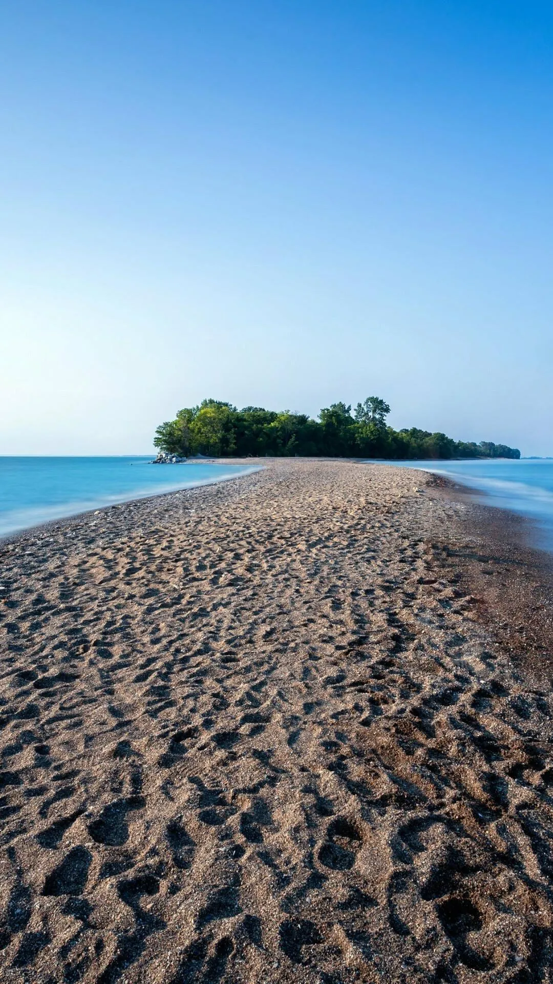 Sandy Path Leading to a Small Green Island in a Calm Sea