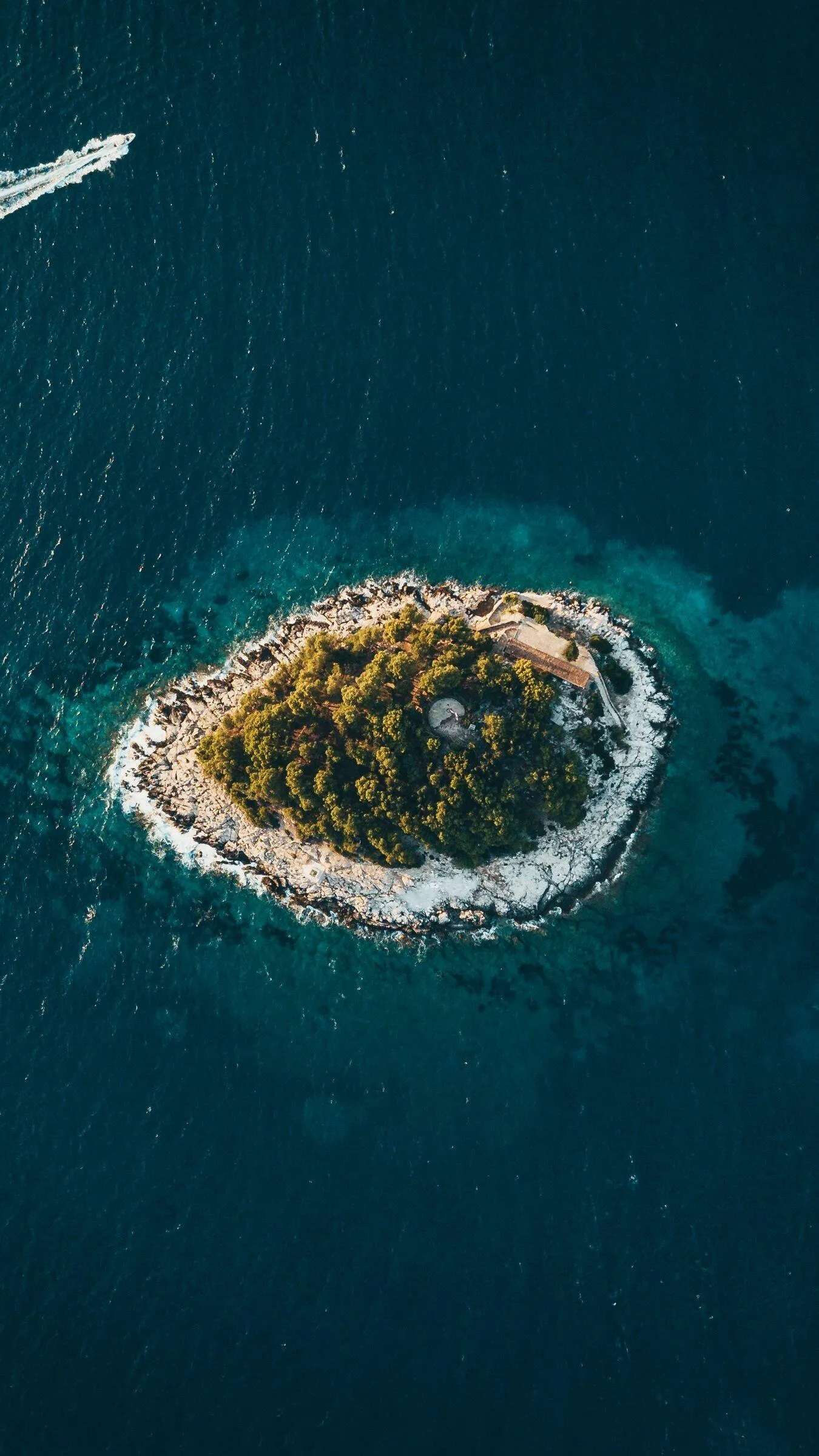 Small Island with Green Trees in a Deep Blue Ocean Wallpaper
