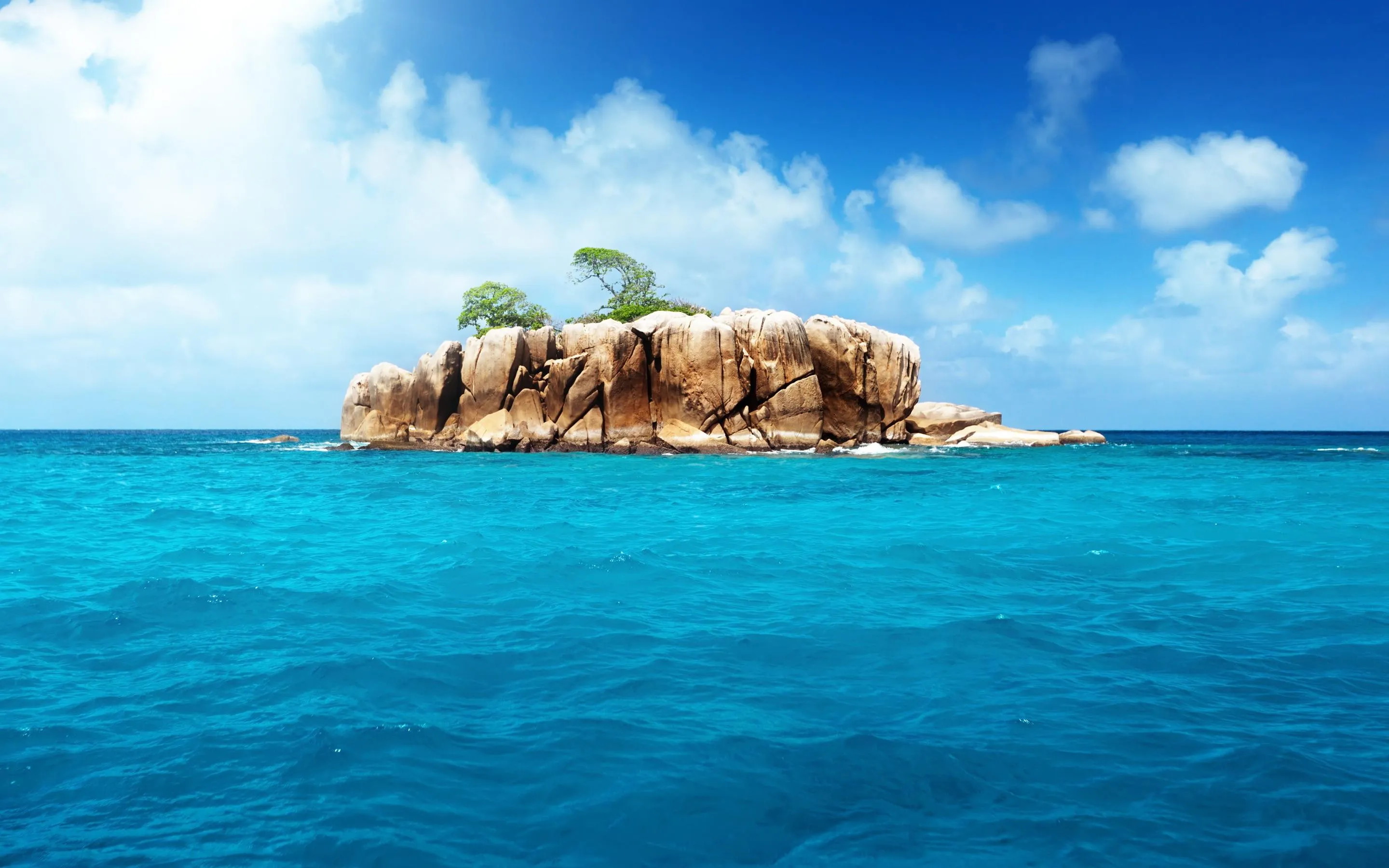 Small Rocky Island Surrounded by Calm Clear Ocean Water
