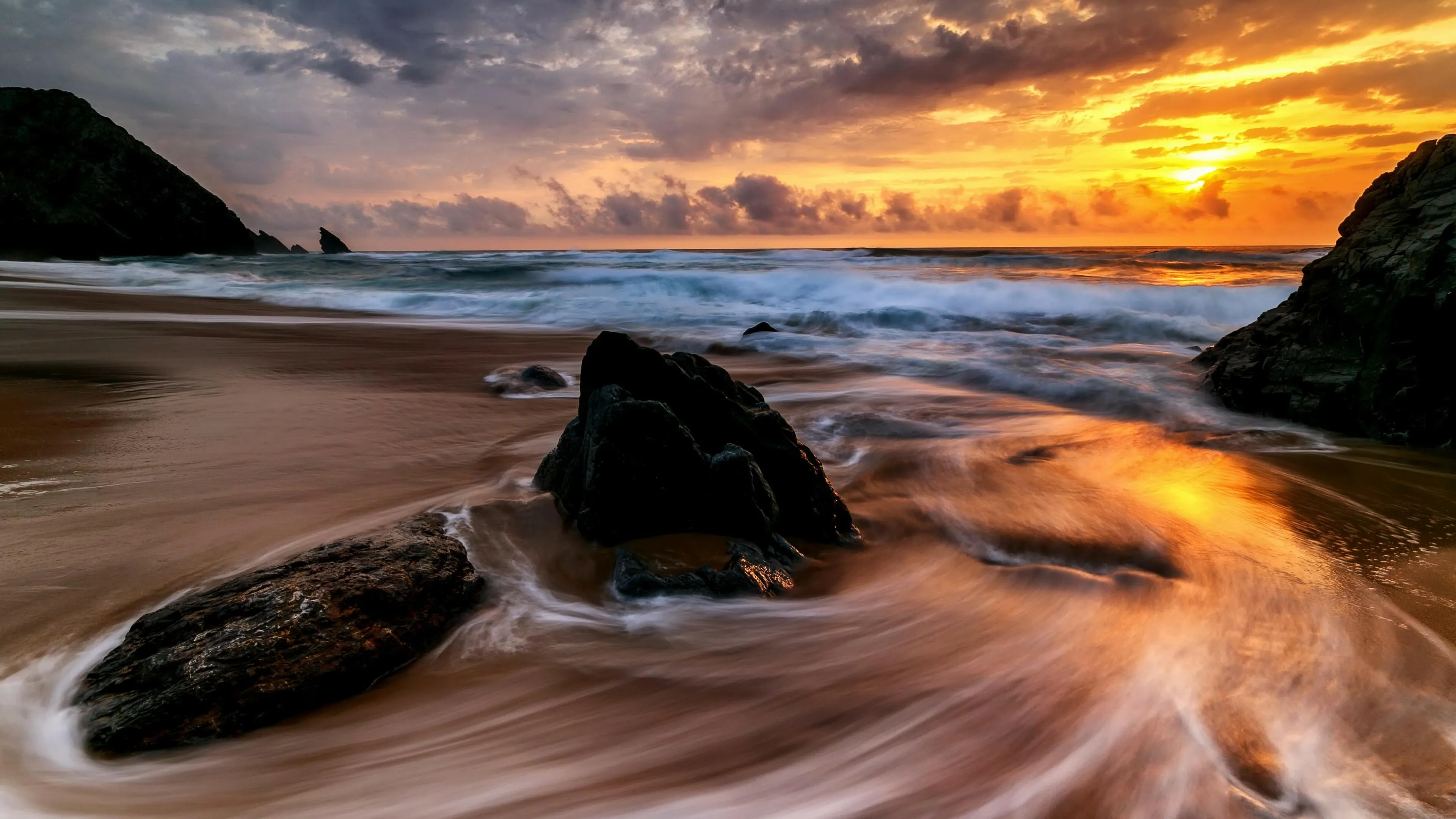 Soft Waves Flowing over Rocks During Sunset Free Wallpaper