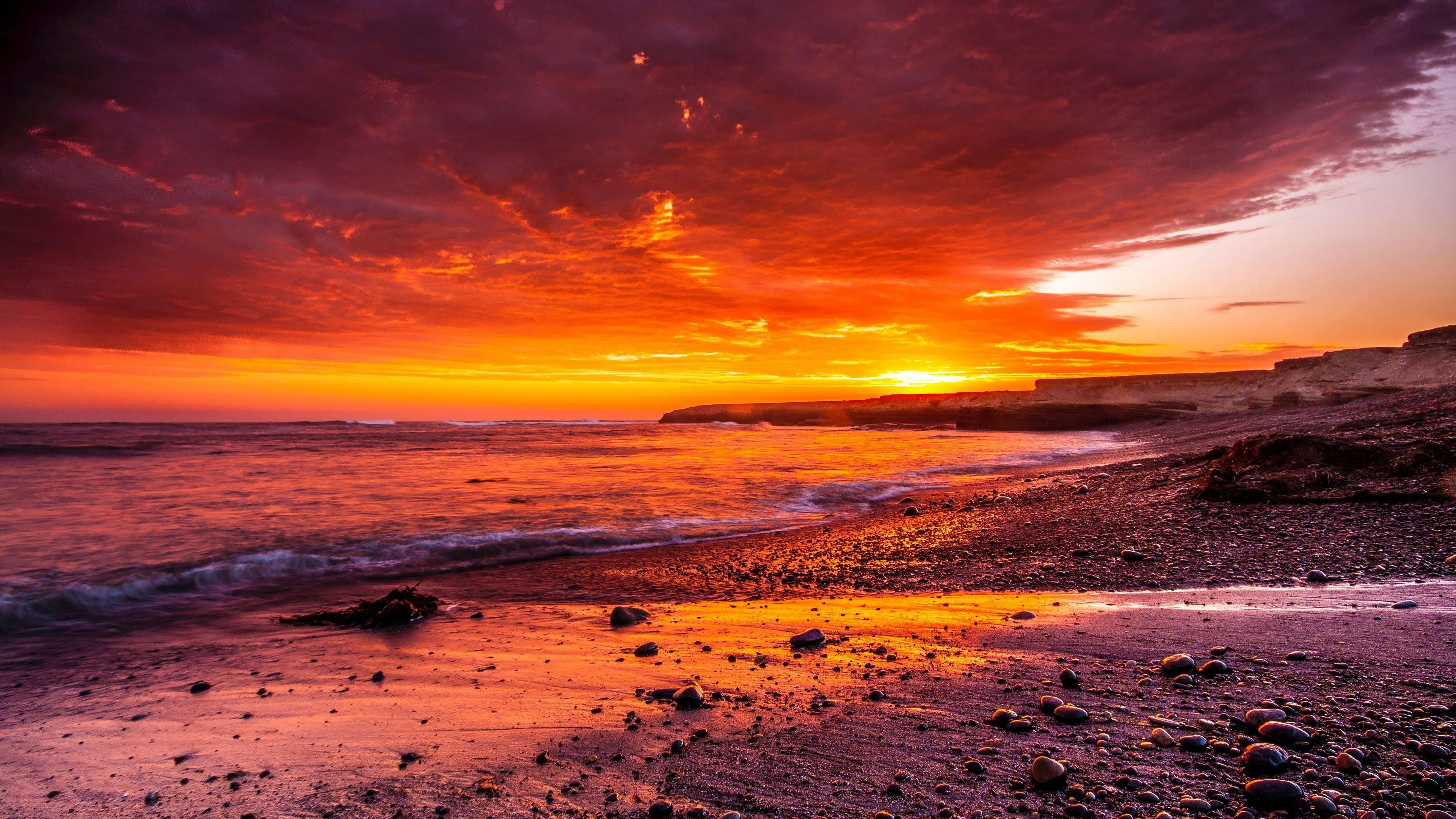 Stunning Sunset over Rocky Beach and Glowing Sky Wallpaper